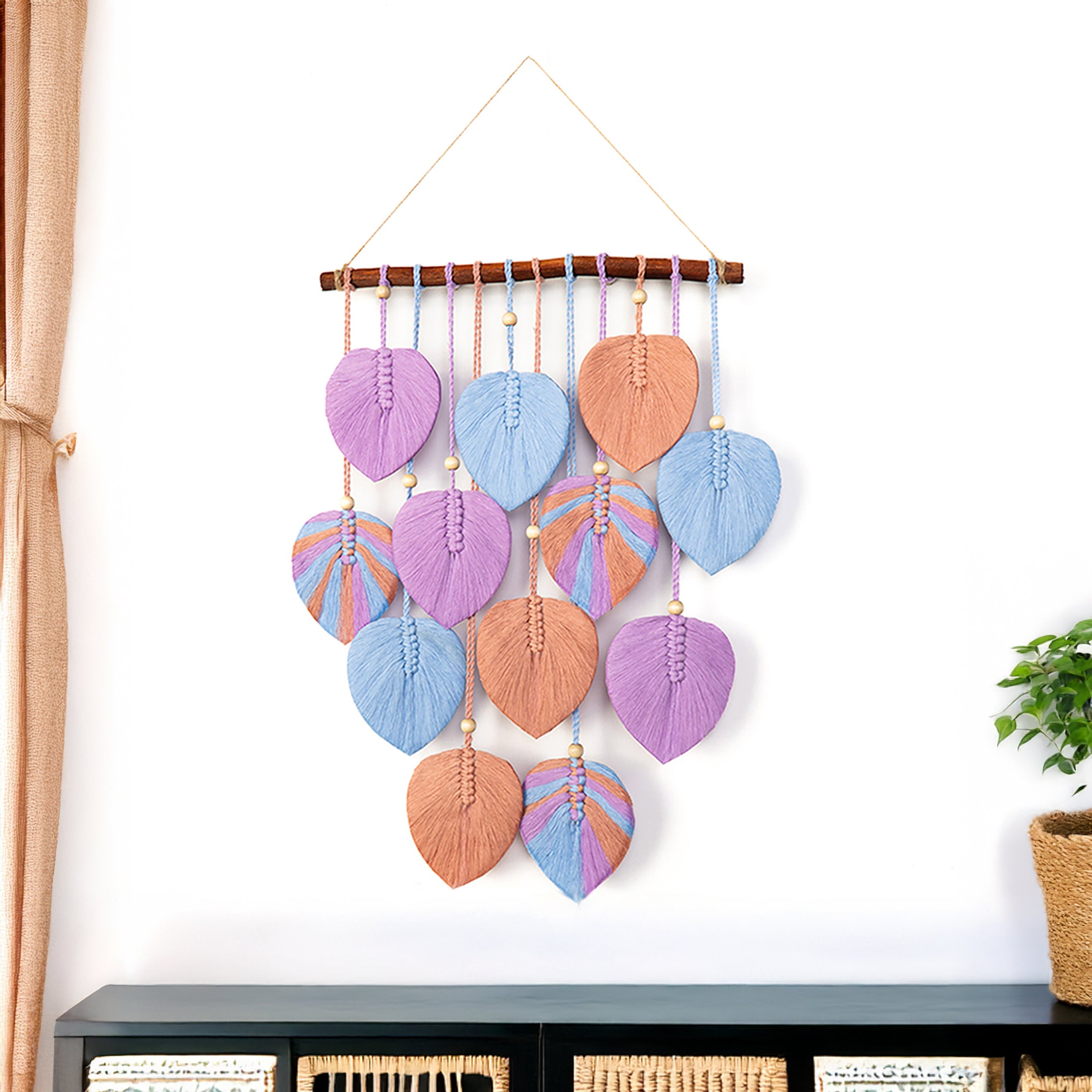 Decorative wall hanging with colorful leaf-shaped beads on a white wall.