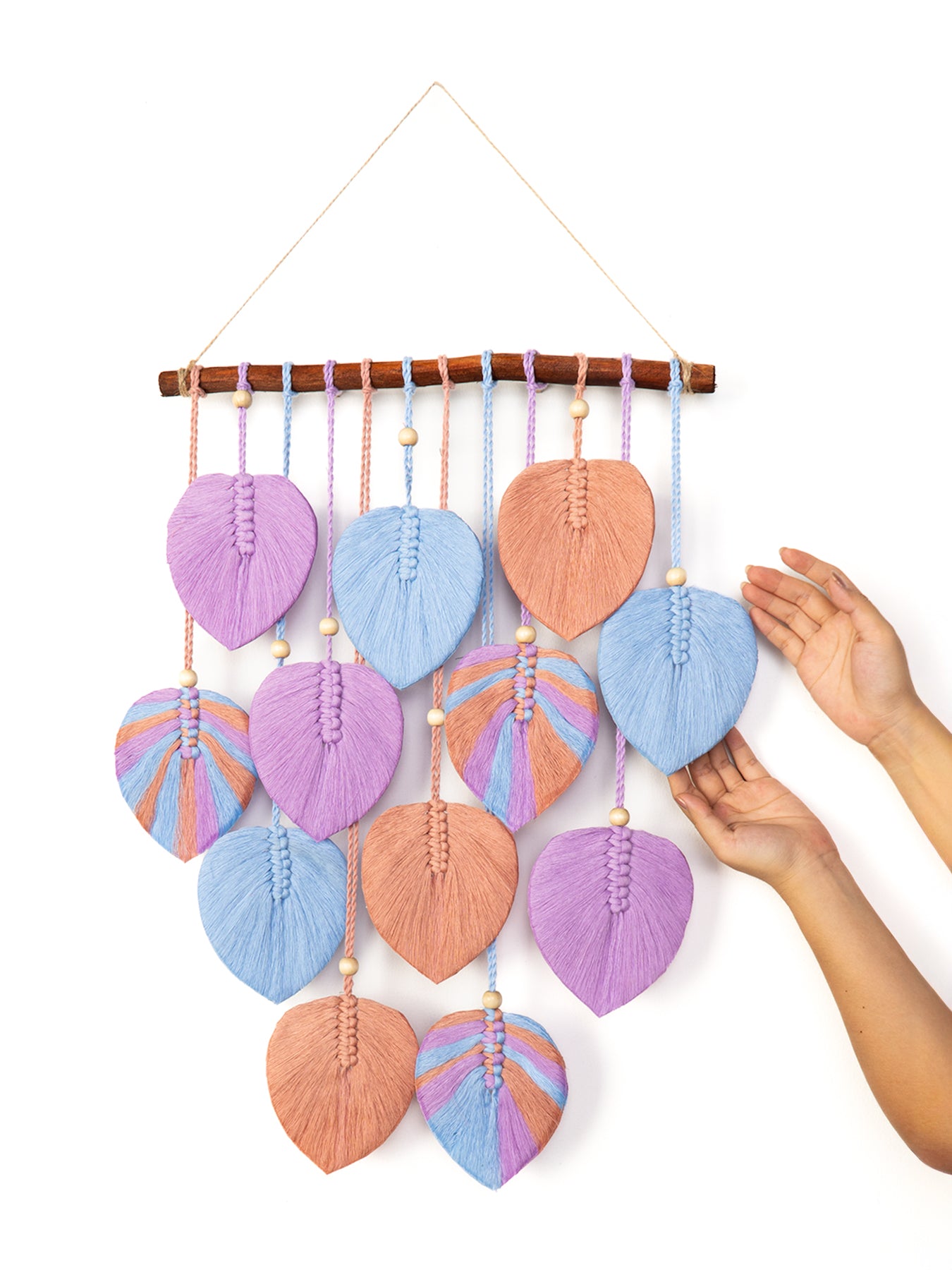 Handmade wall hanging with leaf-shaped green fabric pieces on a white background
