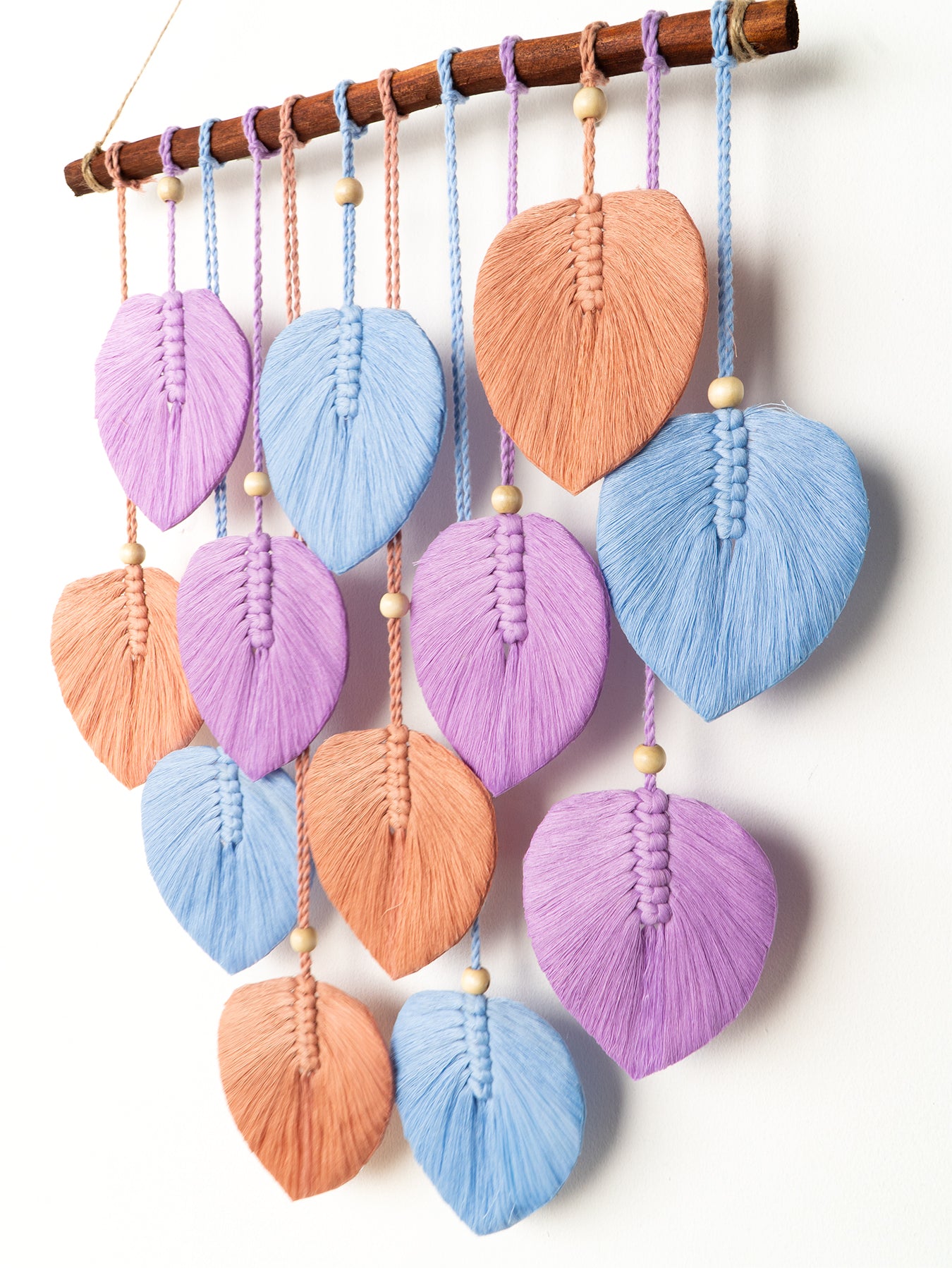 Decorative wall hanging with colorful leaf-shaped macramé elements on a white background