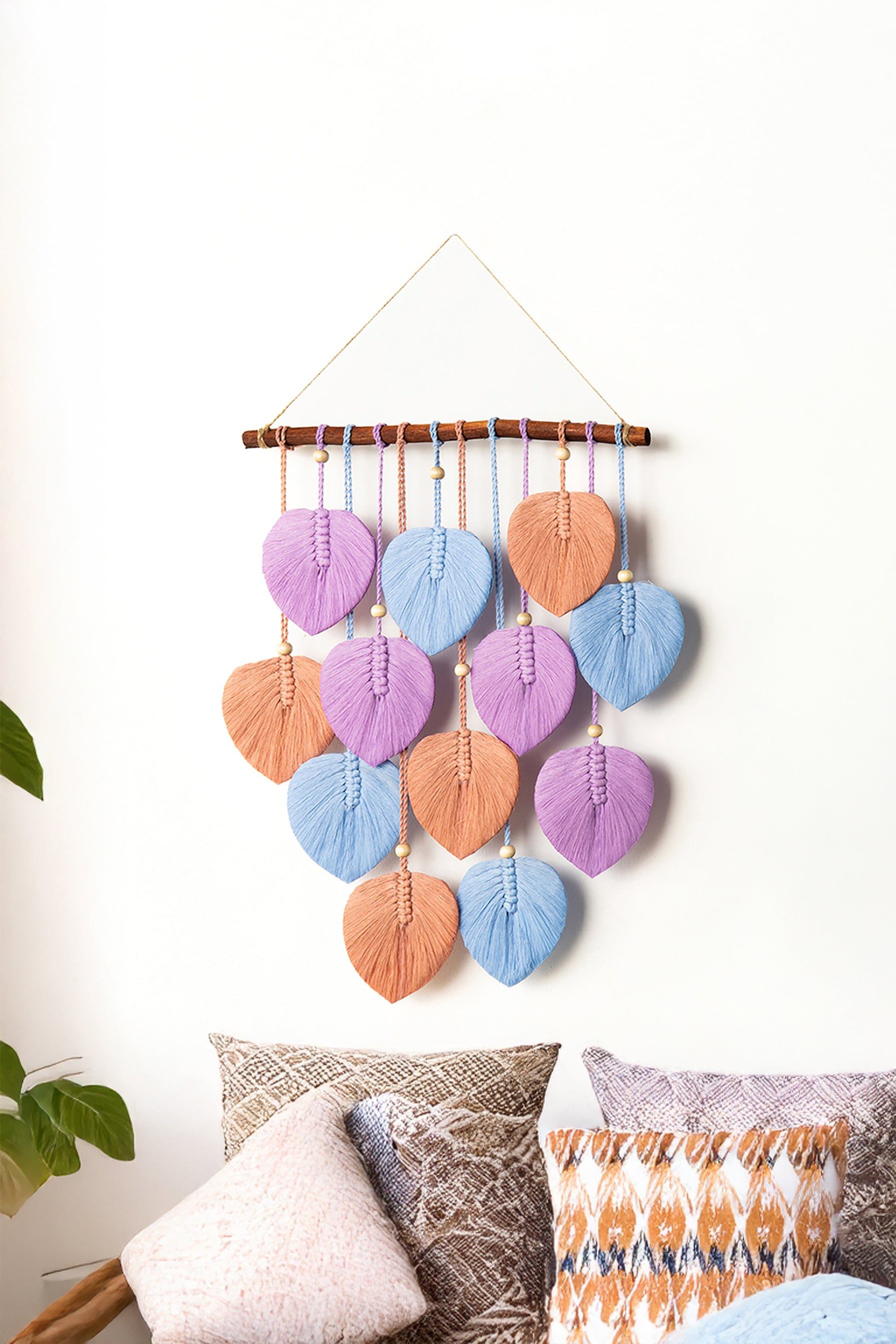 Decorative wall hanging with colorful leaf-shaped beads on a white wall.