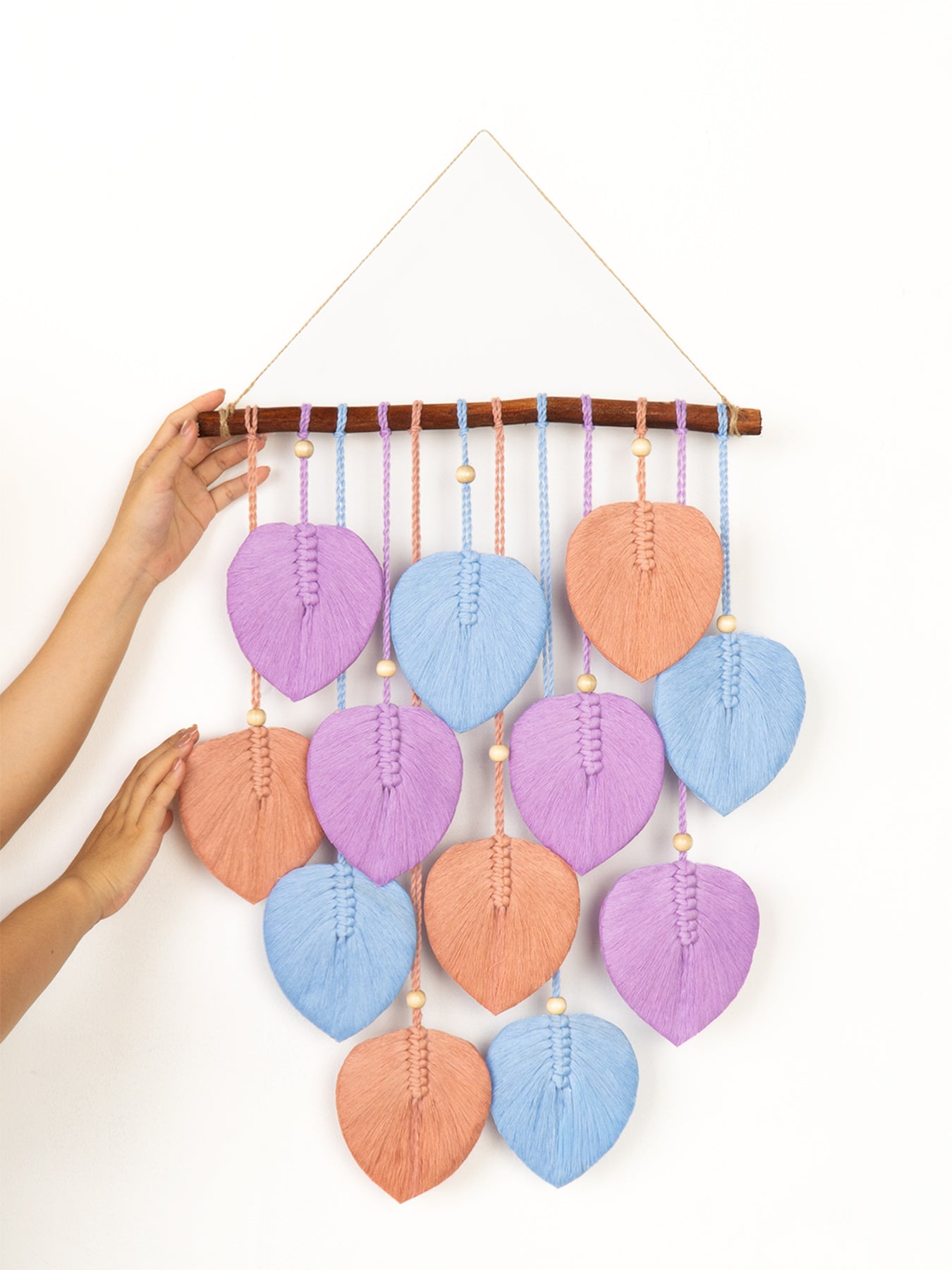 Colorful leaf-shaped wall hanging with beads on a white background