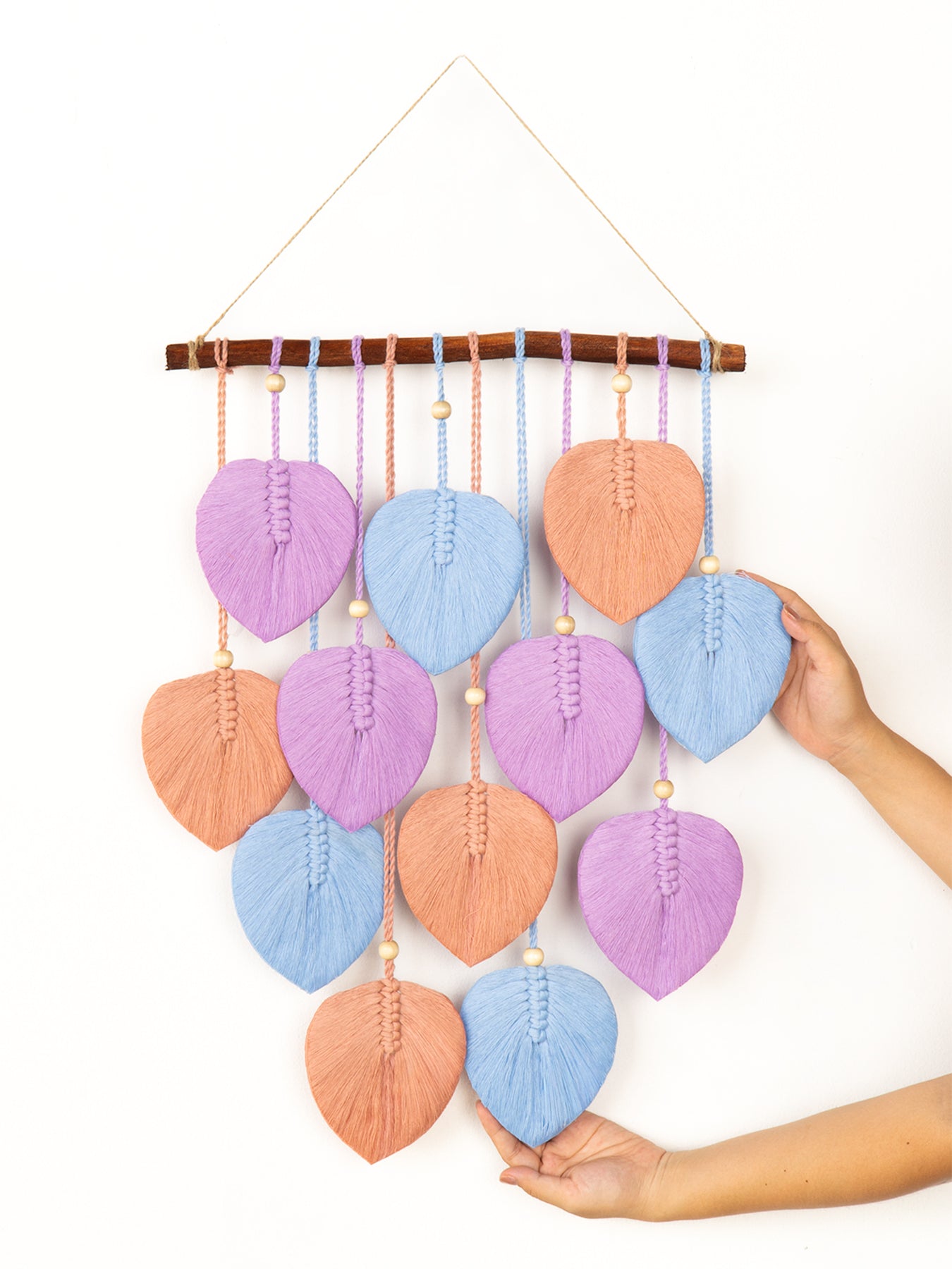 Colorful knitted leaf-shaped mobile hanging on a white background