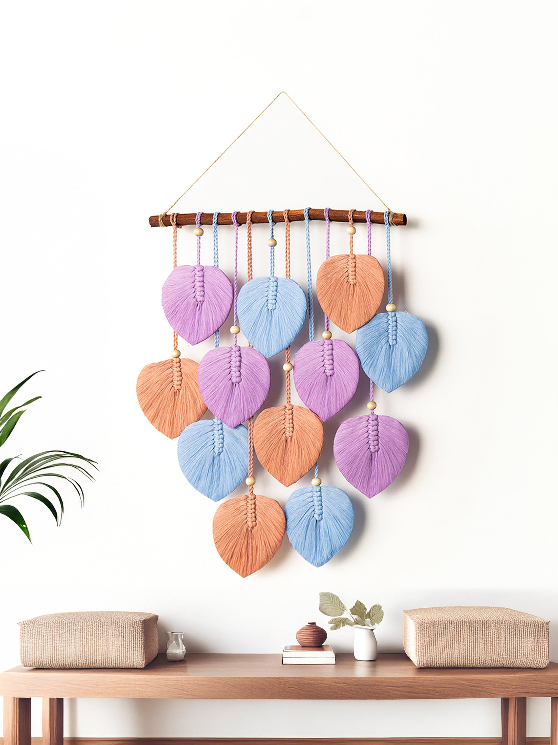 Decorative wall hanging with colorful leaf-shaped elements on a white wall above a wooden table.