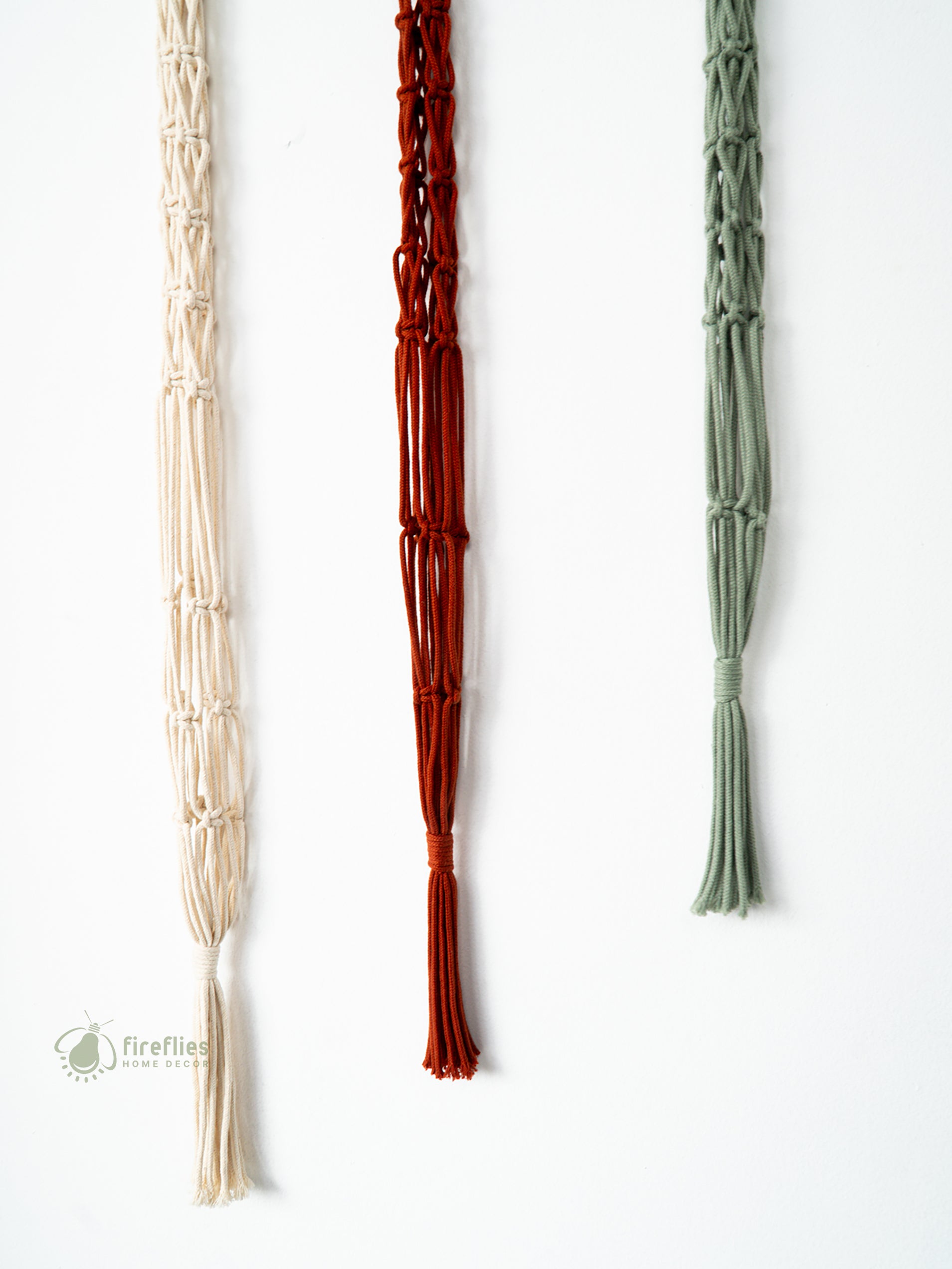 Three woven necklaces in beige, red, and green on a white background.