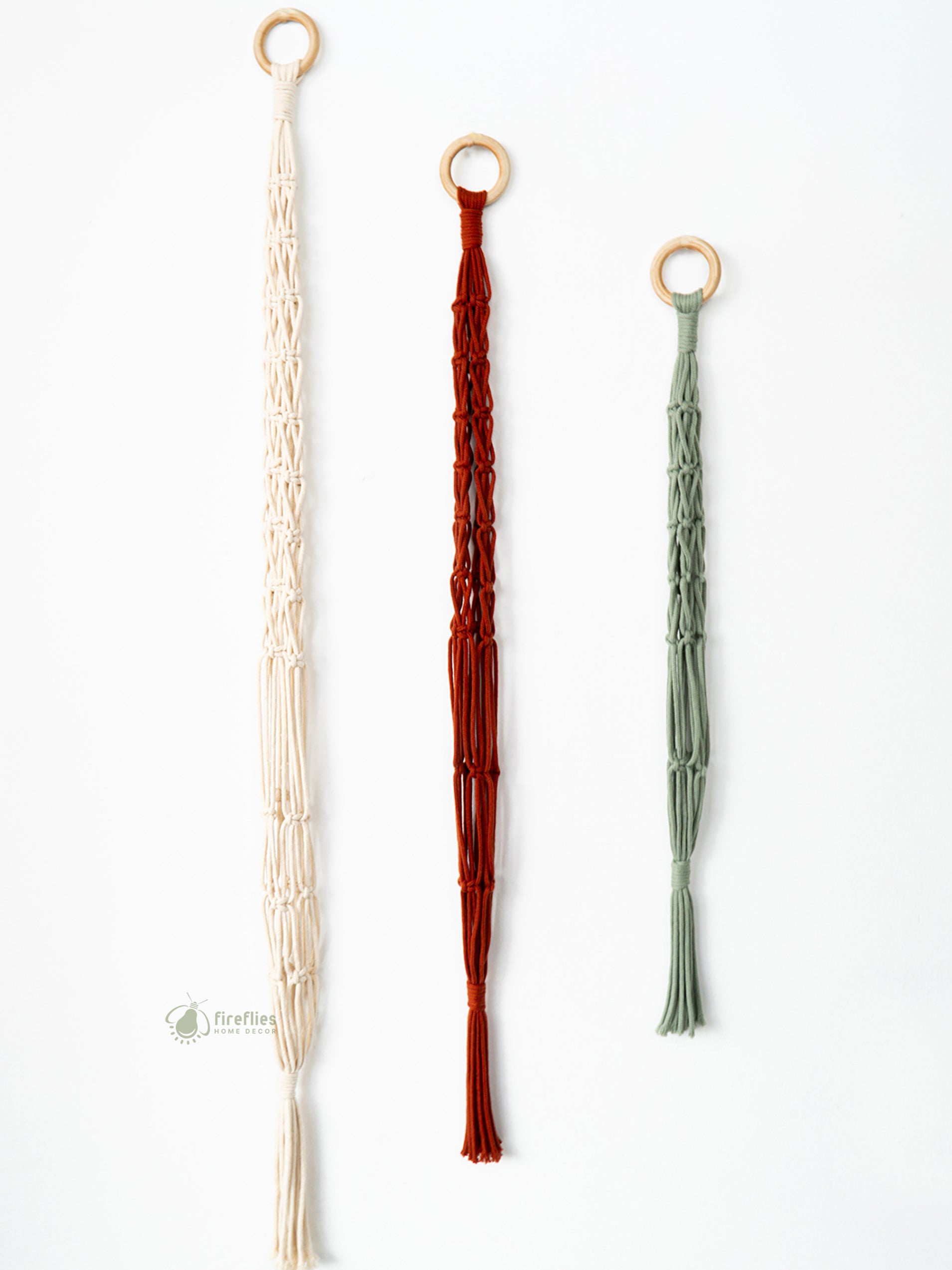 Three decorative tassels in beige, red, and green on a white background