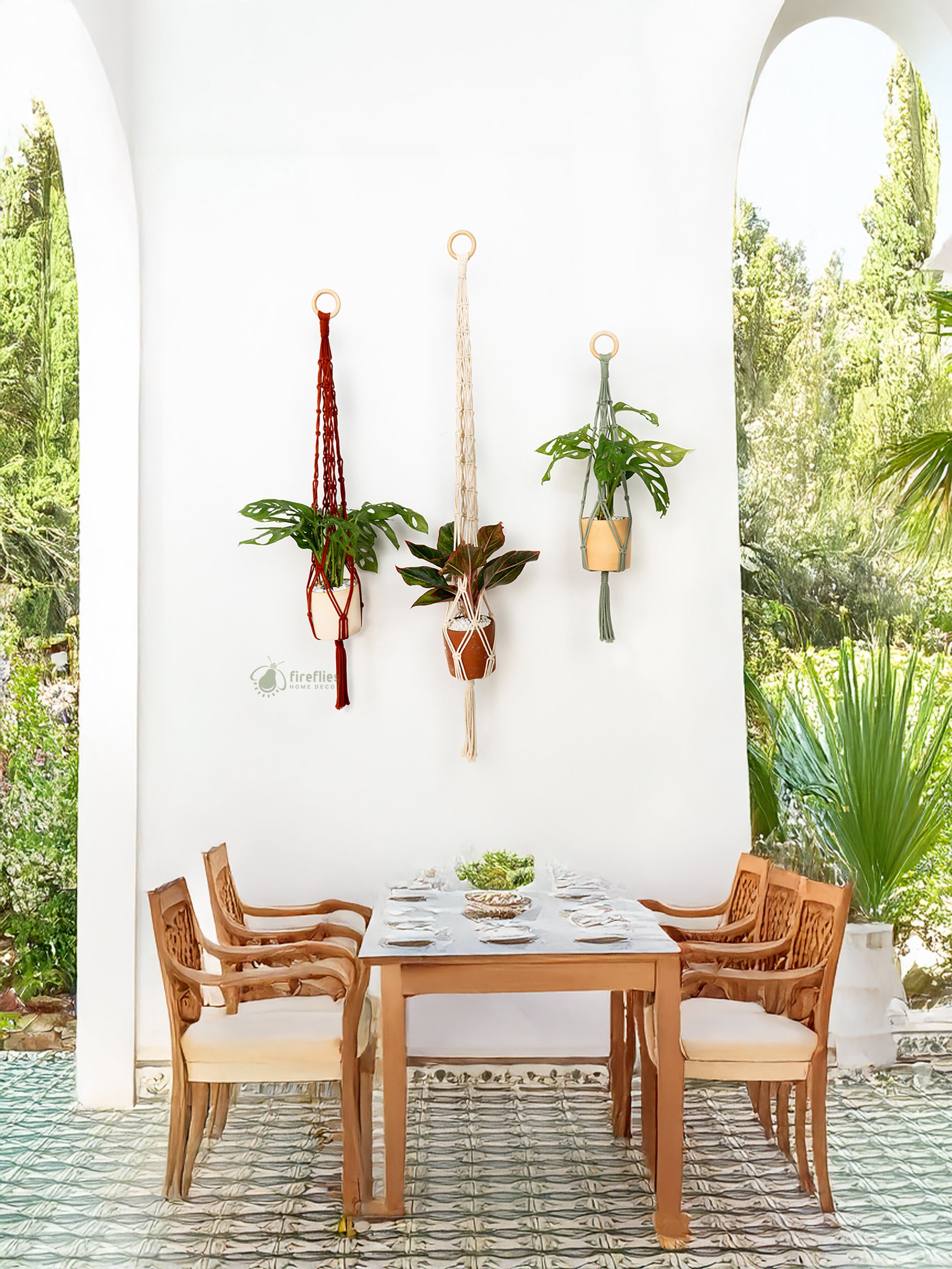Wooden dining table with chairs against a white wall with hanging plants, outdoor setting.