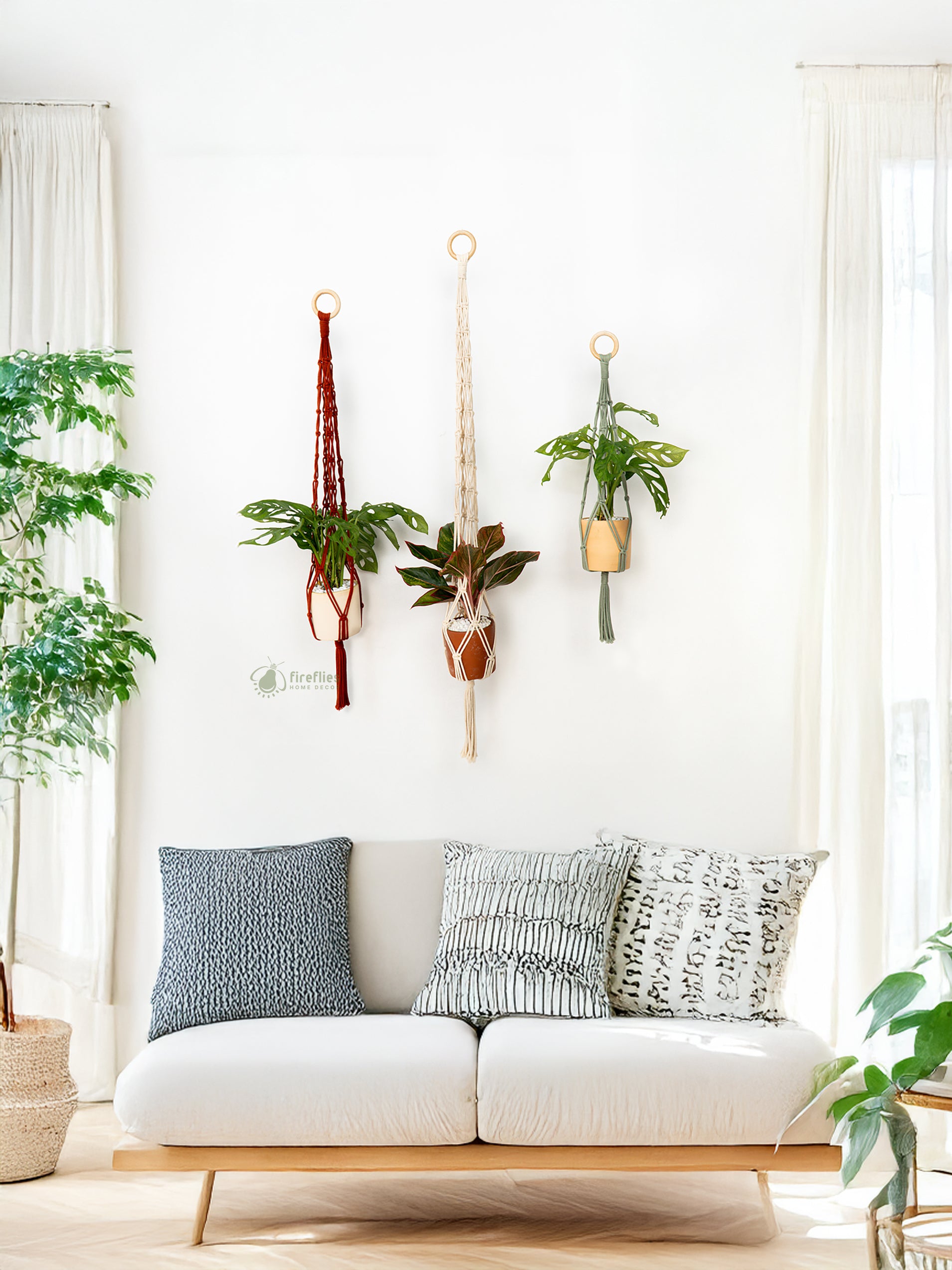 White sofa with decorative pillows in a room with hanging plants and large windows.