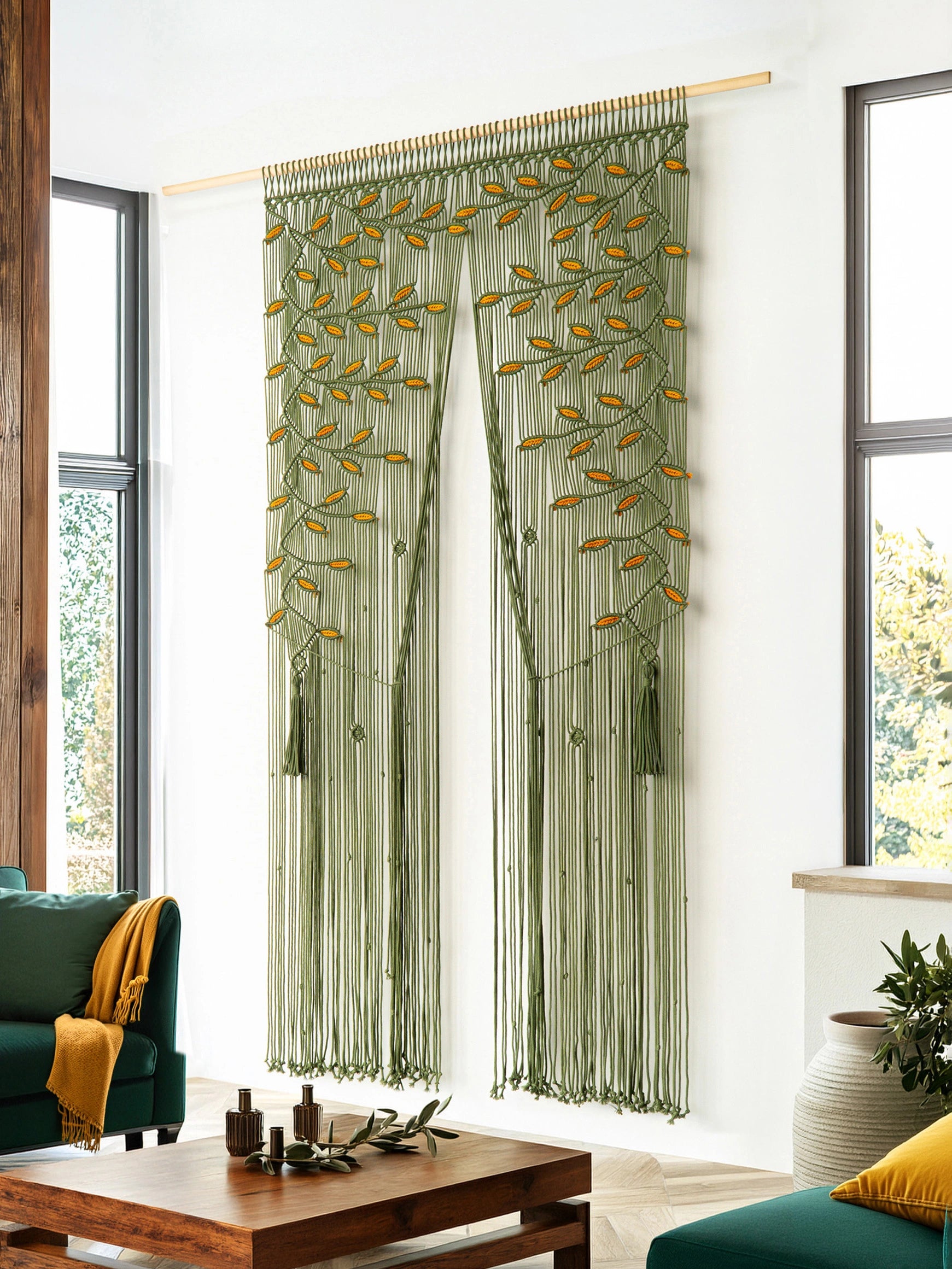 A pair of green sheer curtain panels with embroidered tree branches and yellow-orange leaves, hanging on a gold rod in a bright living room.