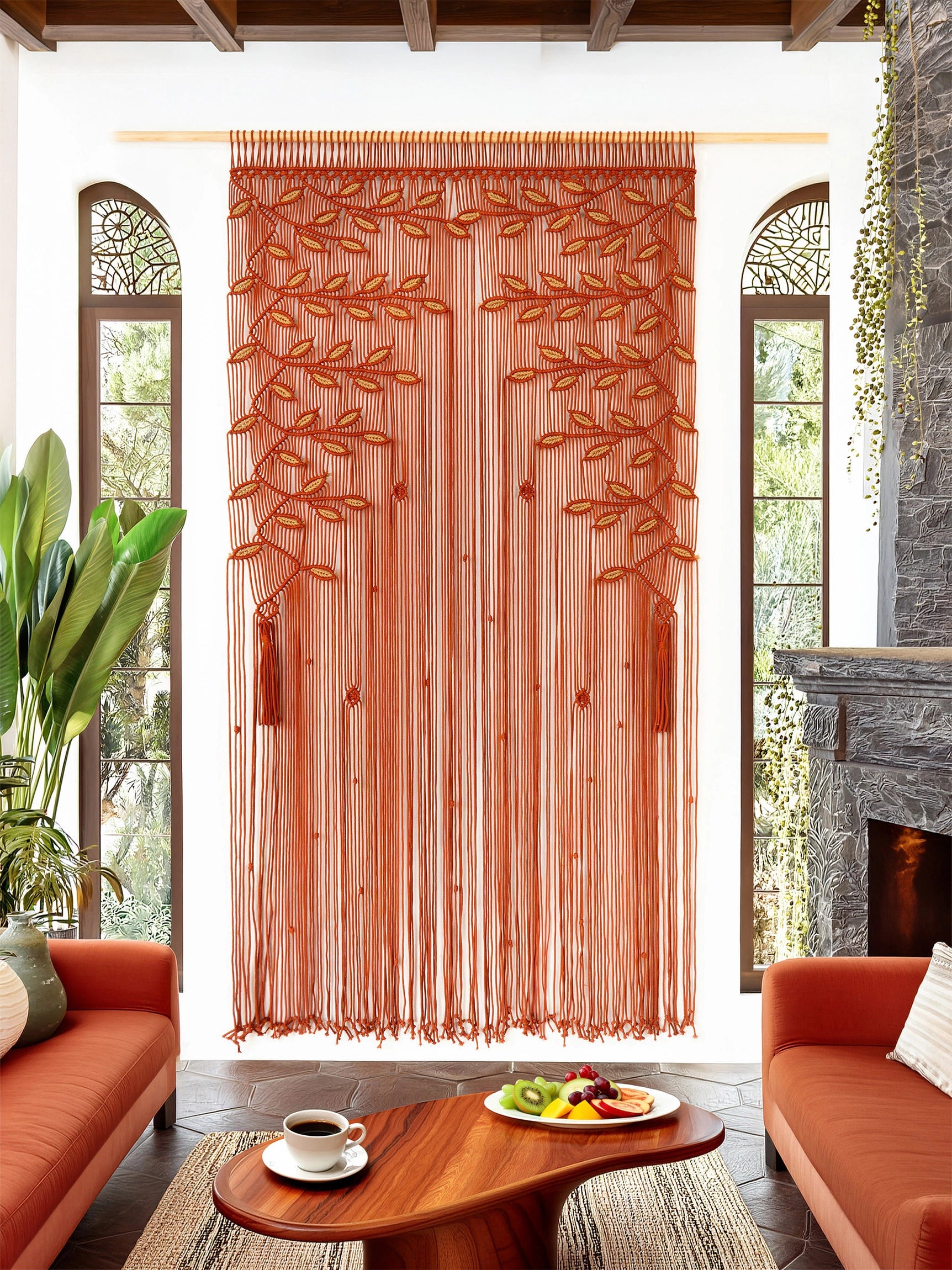 A rust-orange sheer curtain panel with embroidered tree branches and tassel details, hanging in a bright living room with orange sofas, a wooden coffee table, and tall arched windows.