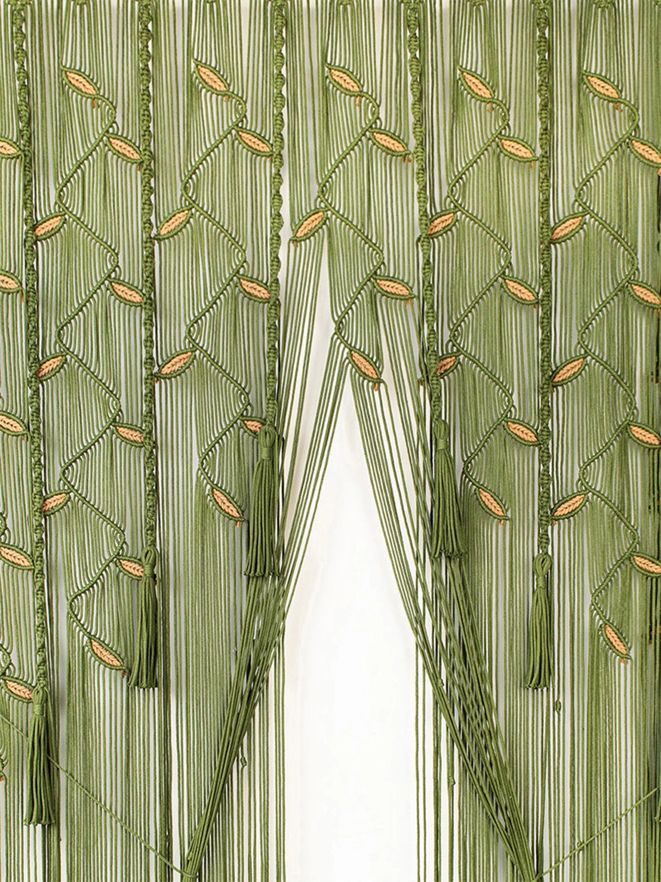 Green beaded curtain with vertical strands, woven diamond patterns, and small oval bead accents, shown hanging in front of a white opening.