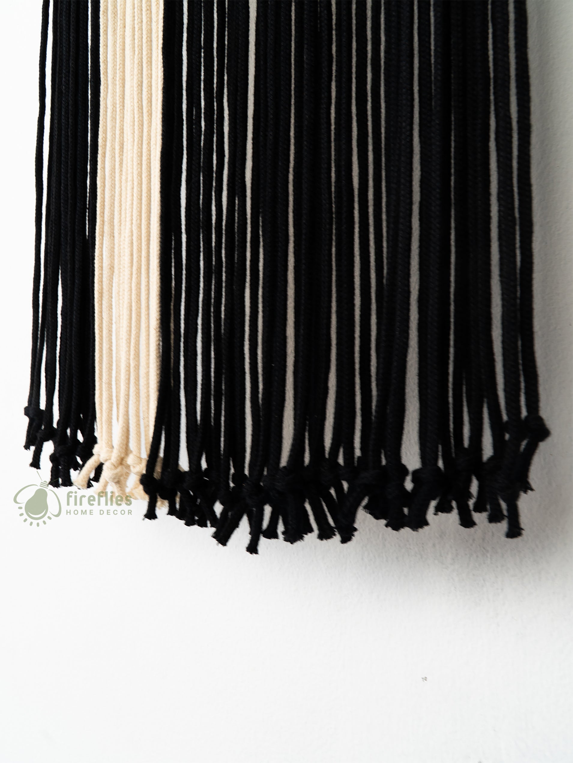 Black tassel scarf with beige accents on a white background