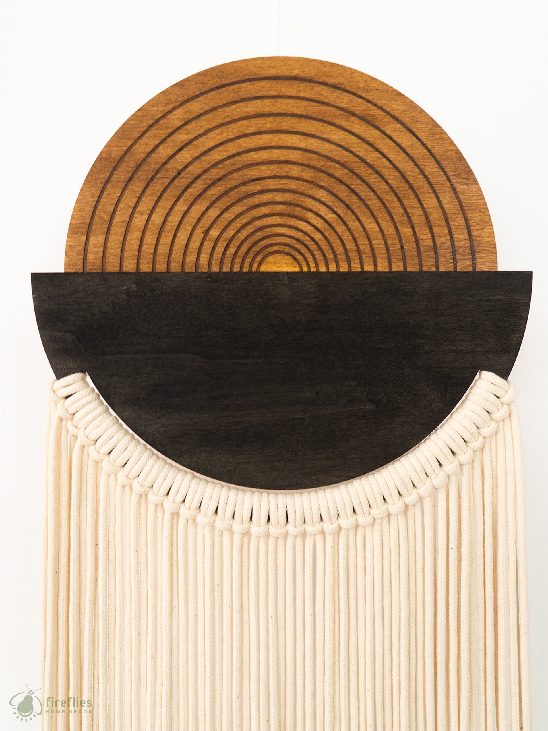 Decorative wall hanging with concentric circle pattern and fringe details on a white background