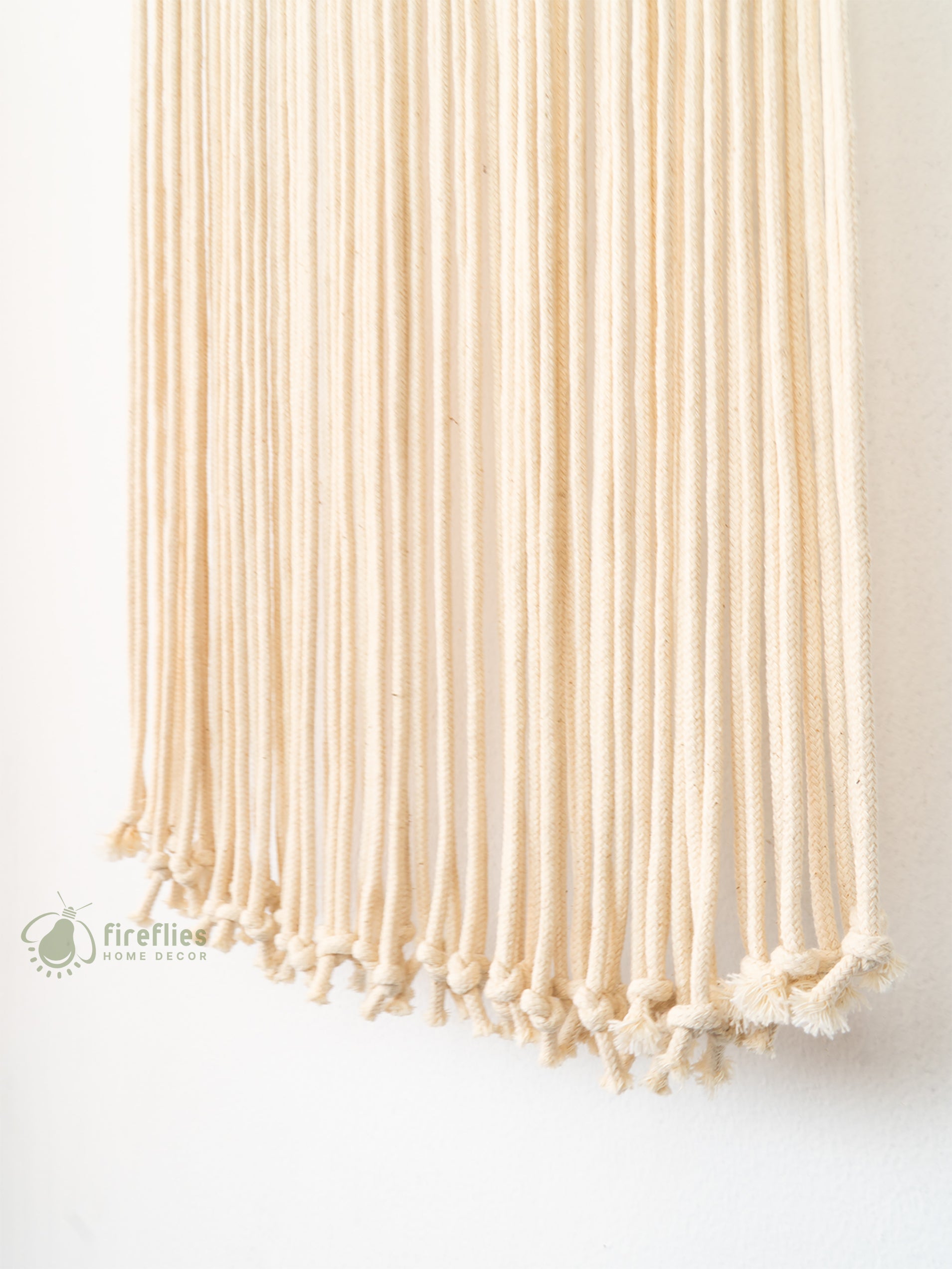 Beige woven wall hanging with tassels on a white background, featuring the Firefly Home Decor logo.