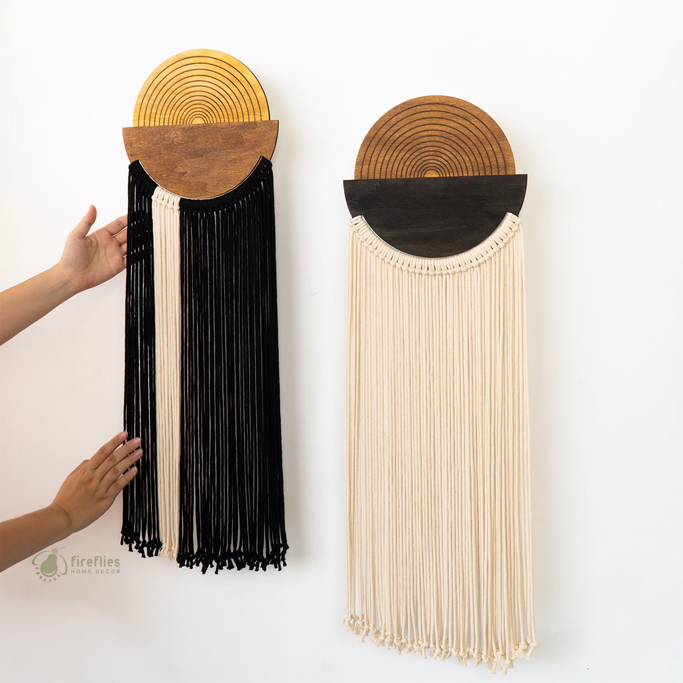 Two wall hangings with wooden circular tops and fringe details on a white background.