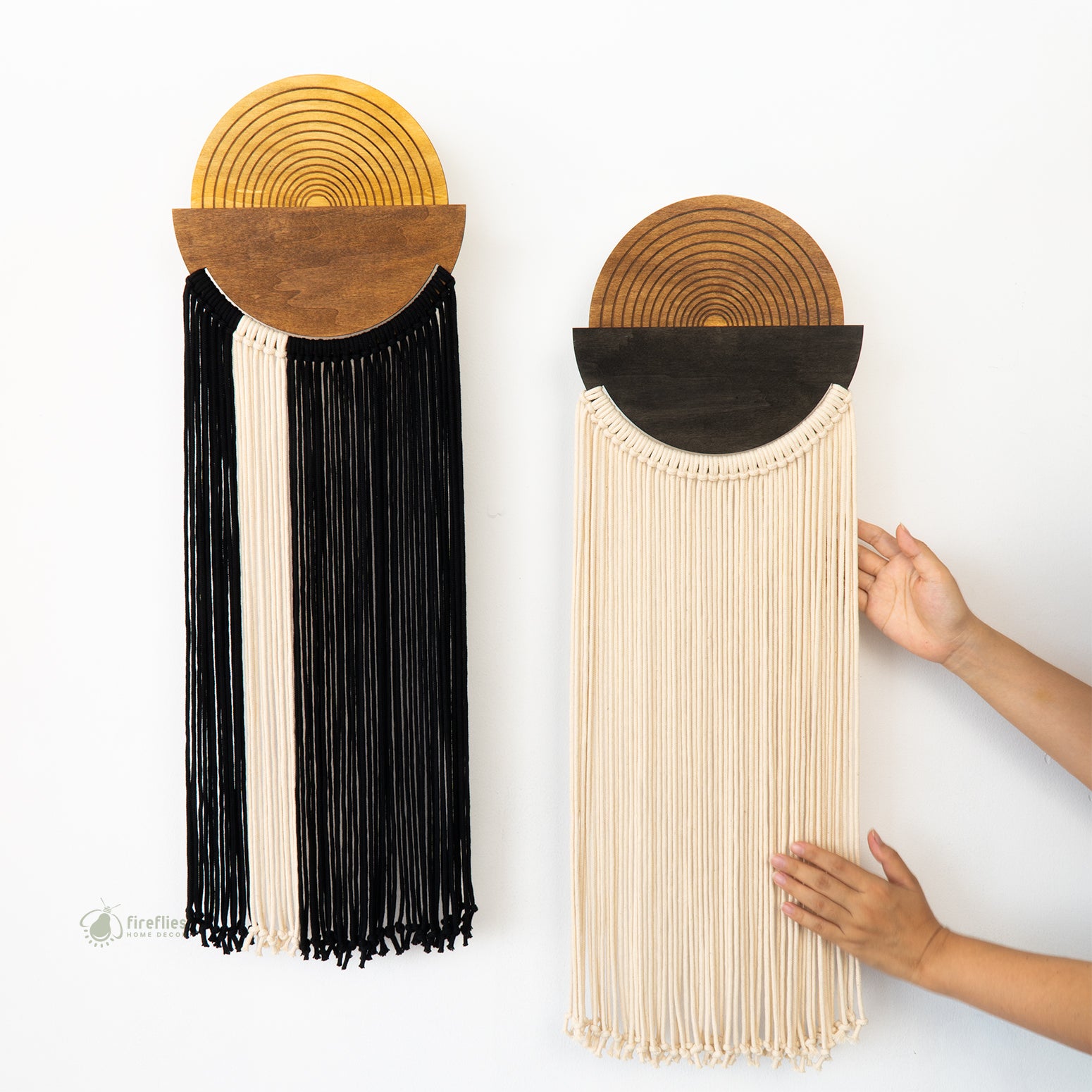 Two wall hangings with black and beige fringe on a white background