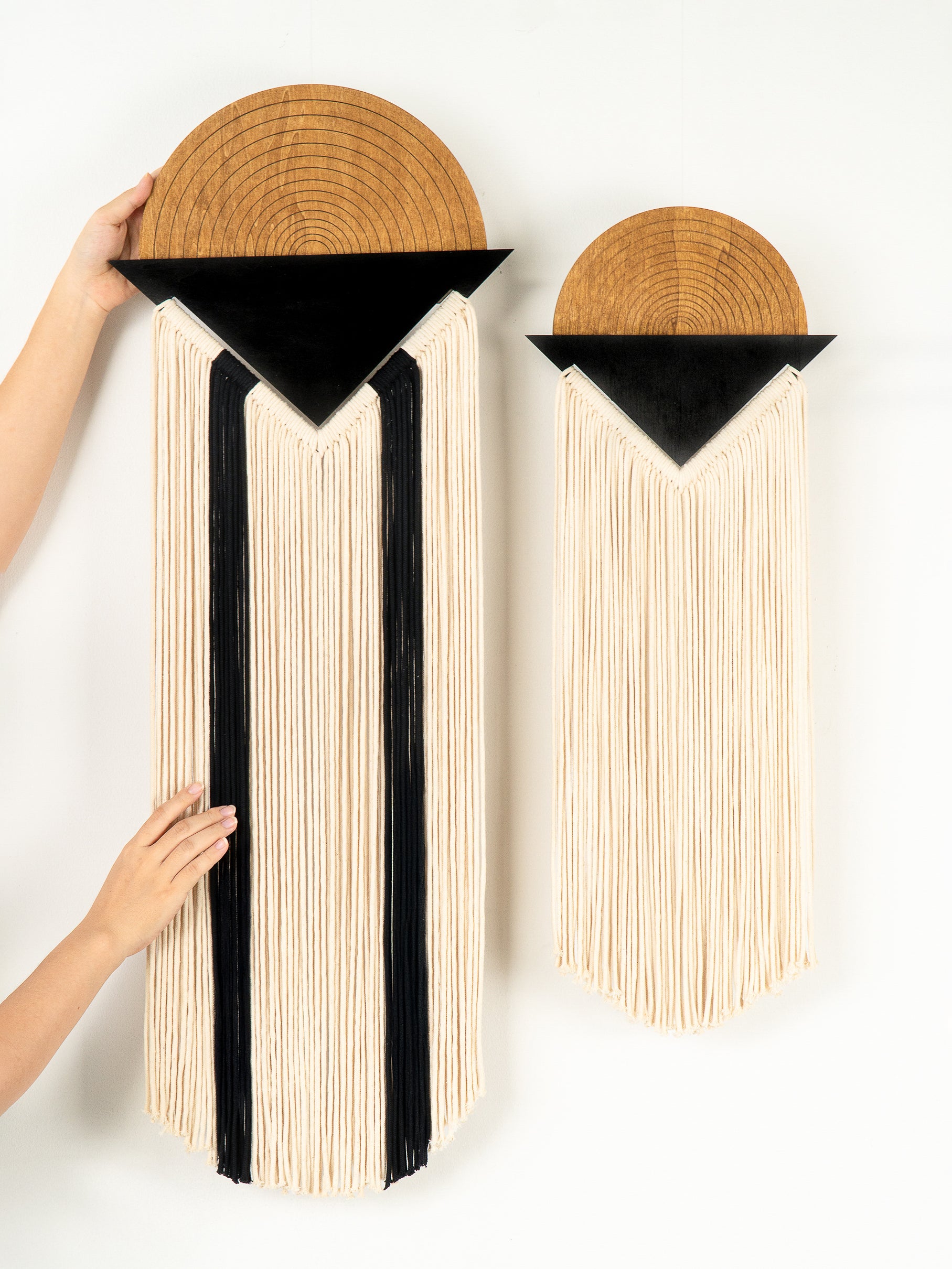 Two wall-mounted shelves with wooden tops and black triangular accents, held by a person.