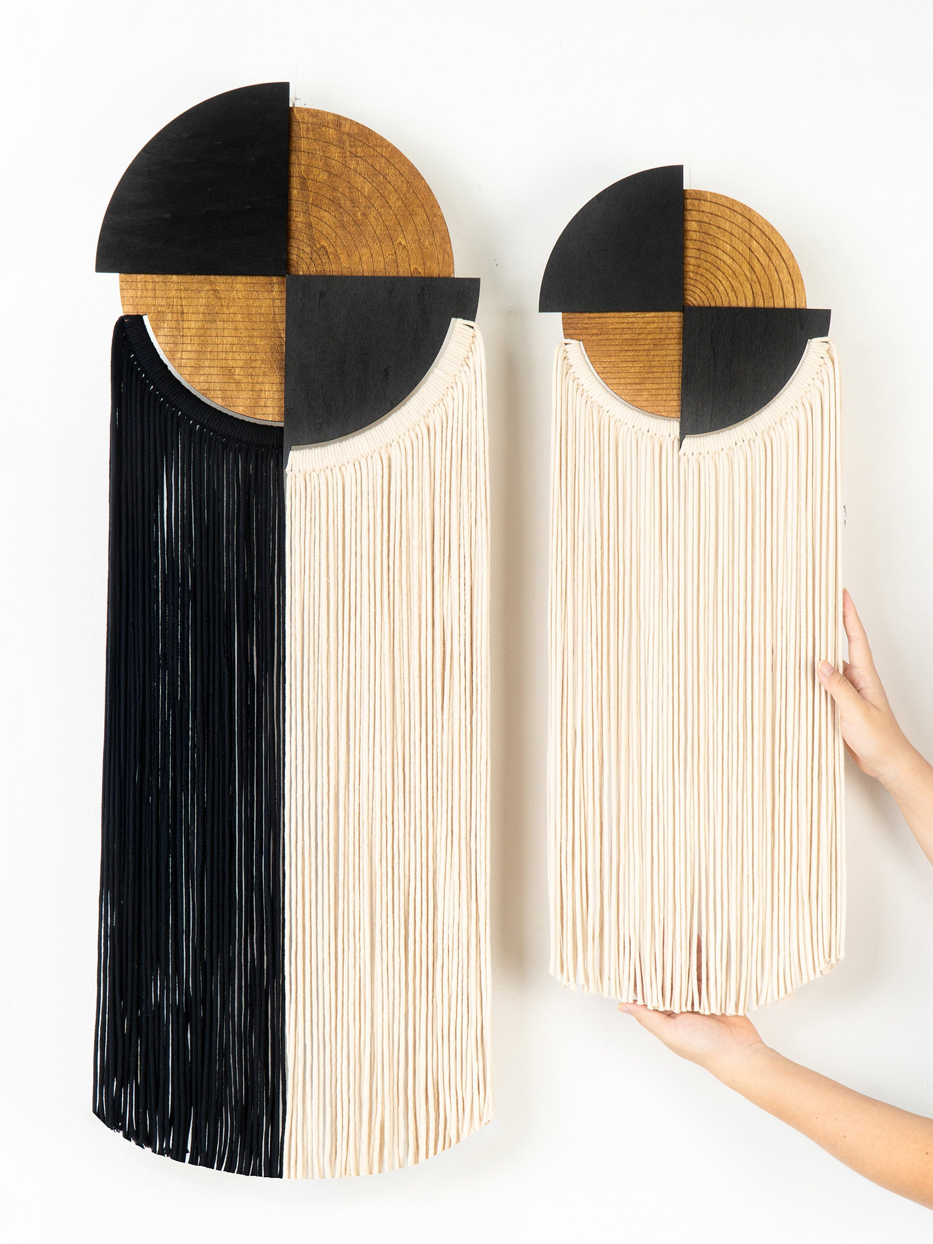 Two book-shaped wall art pieces with wooden tops and black and white interiors on a white background.