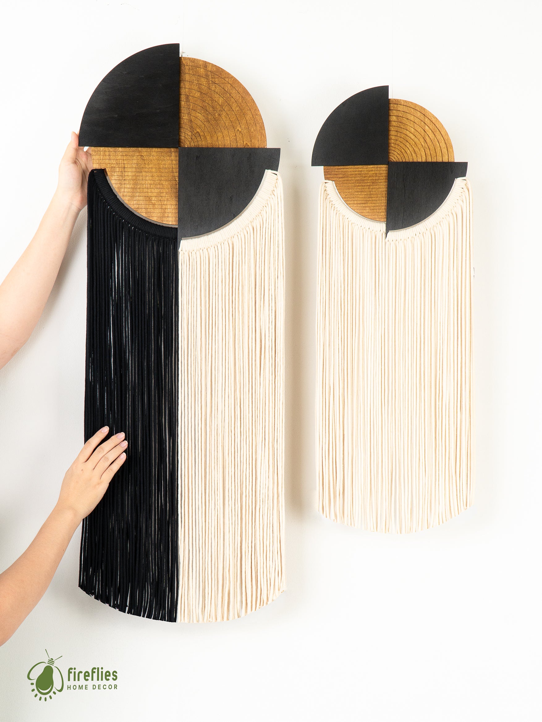 Two decorative wall hangings with geometric designs and long fringe on a white background, featuring the Fireflies Home Decor logo.