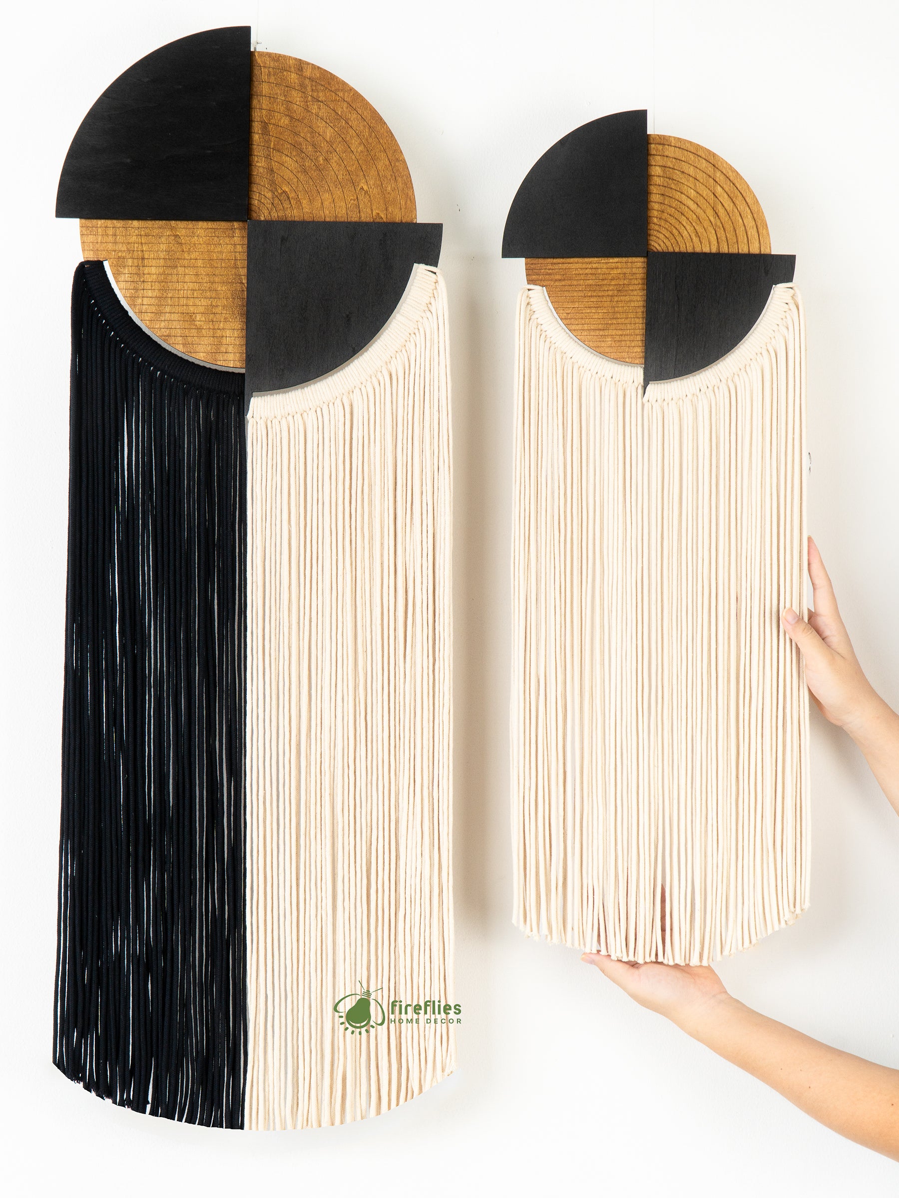 Two wall art pieces with geometric design held by a hand on a white background.