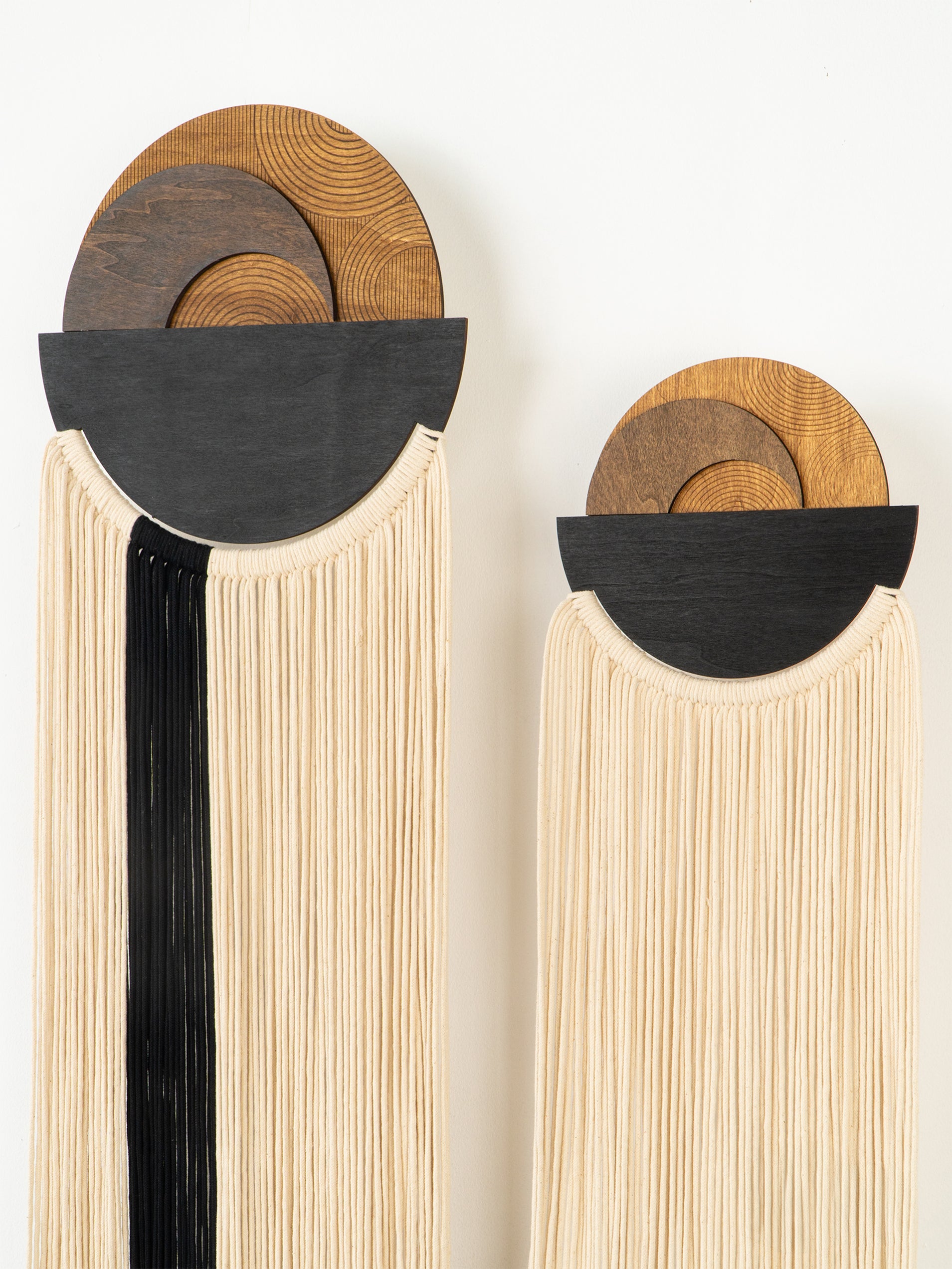 Two decorative wall pieces with circular wooden tops and black and white ribbed bases on a white background.