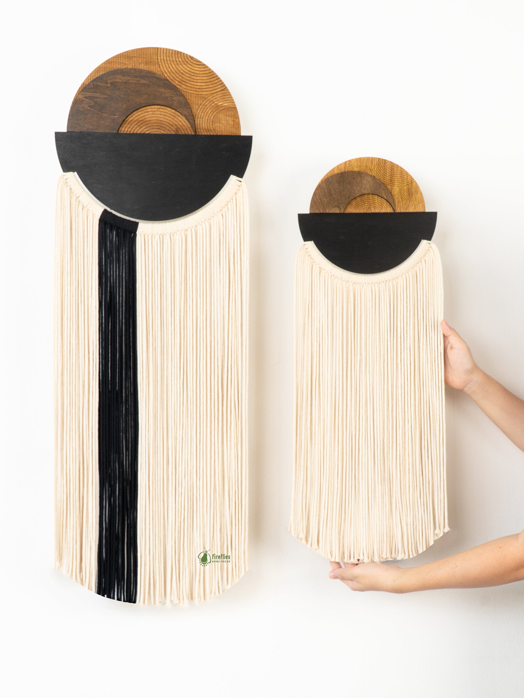 Two wall-mounted wooden boards with black and white fringe on a white background