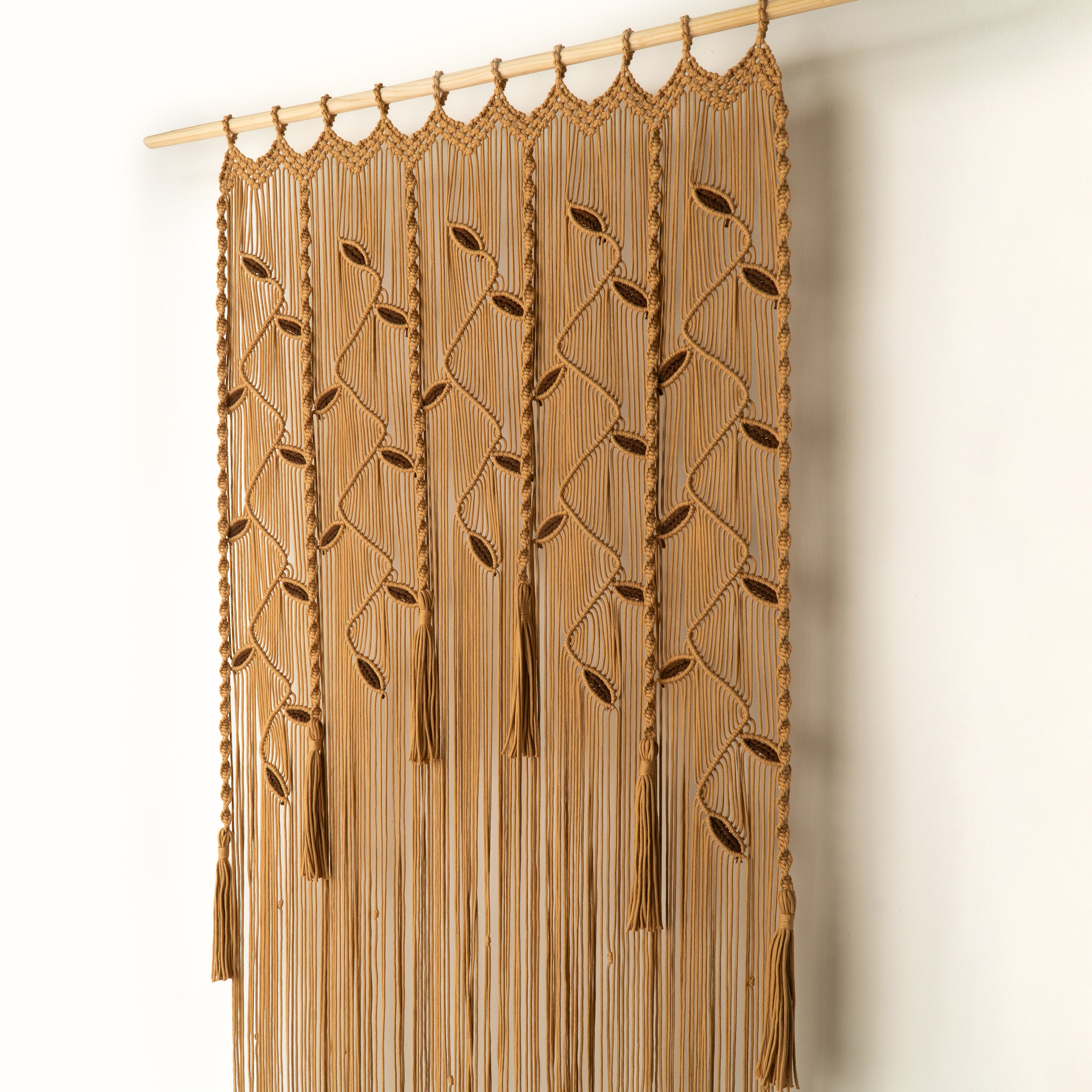 Brown macrame curtain hanging against a white wall