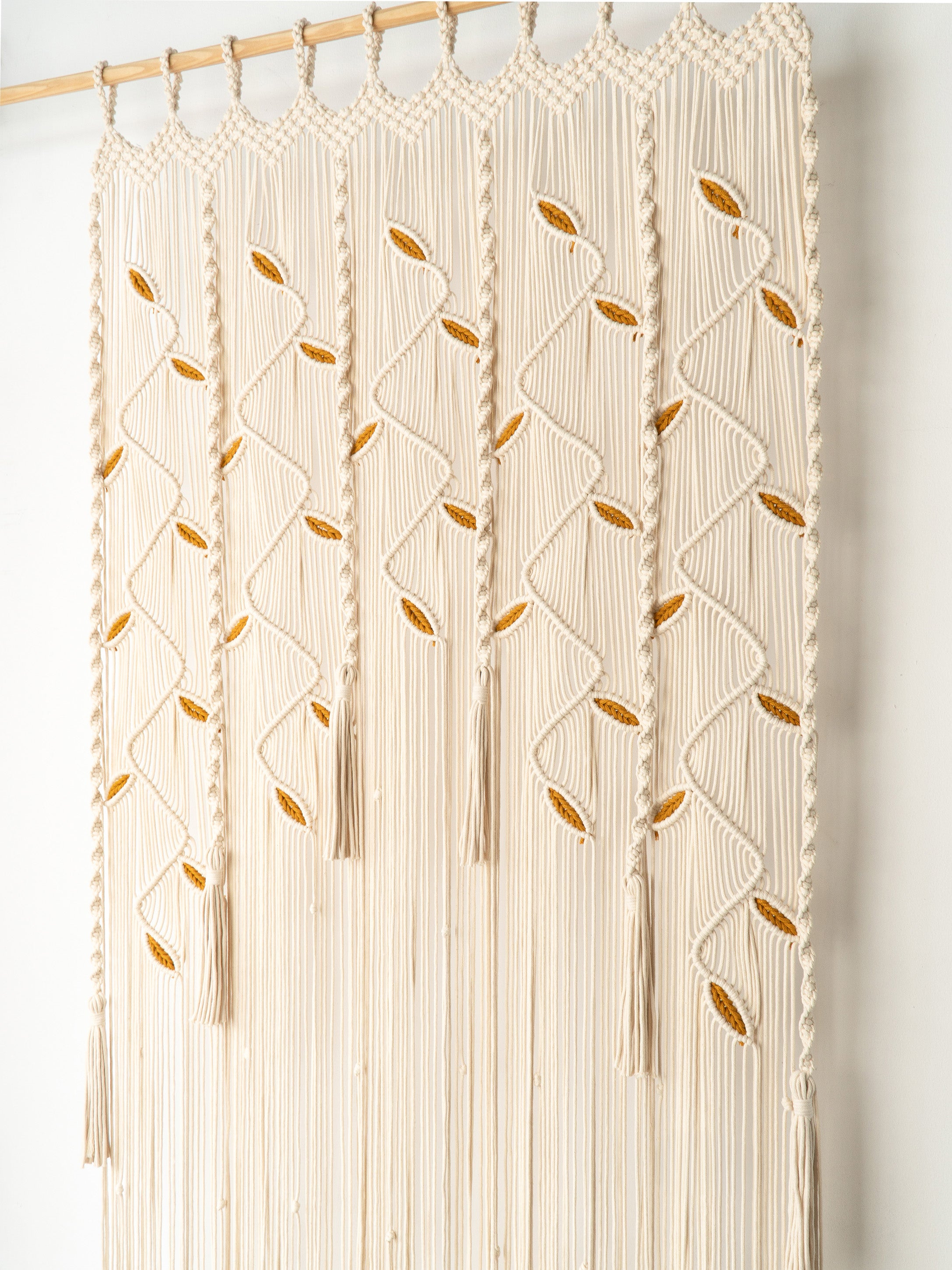 Macrame wall hanging with geometric pattern and tassels on a white background