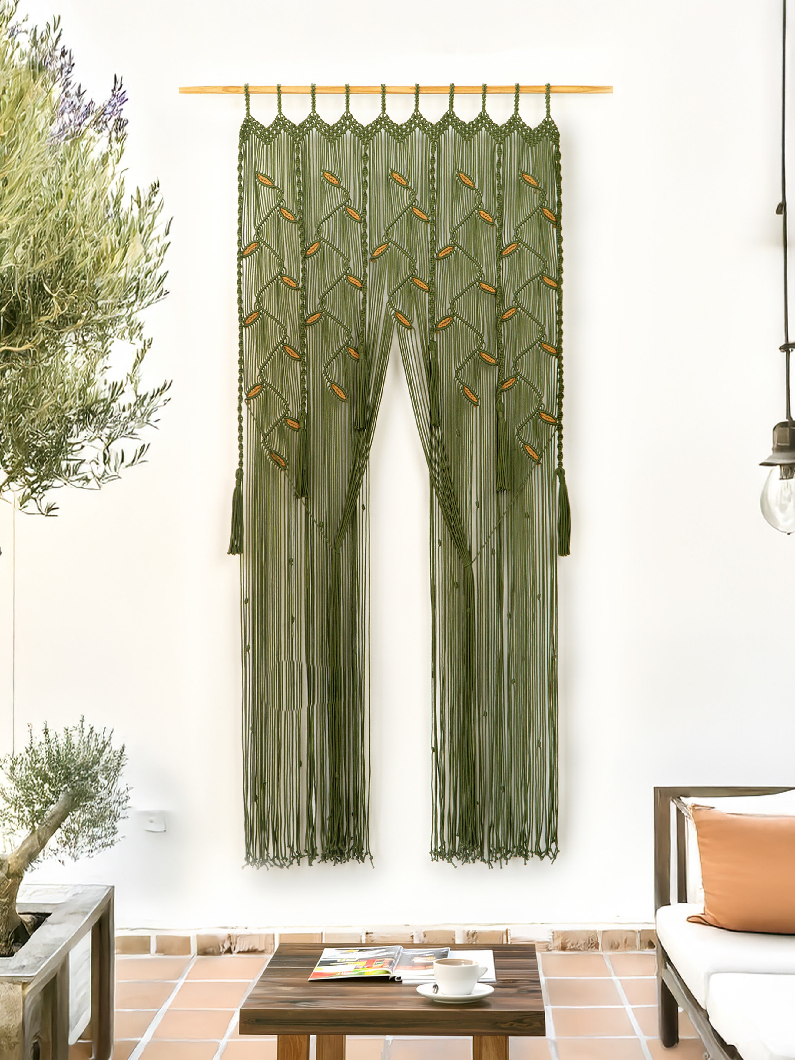 Green macrame curtain hanging in a room with plants and a table.