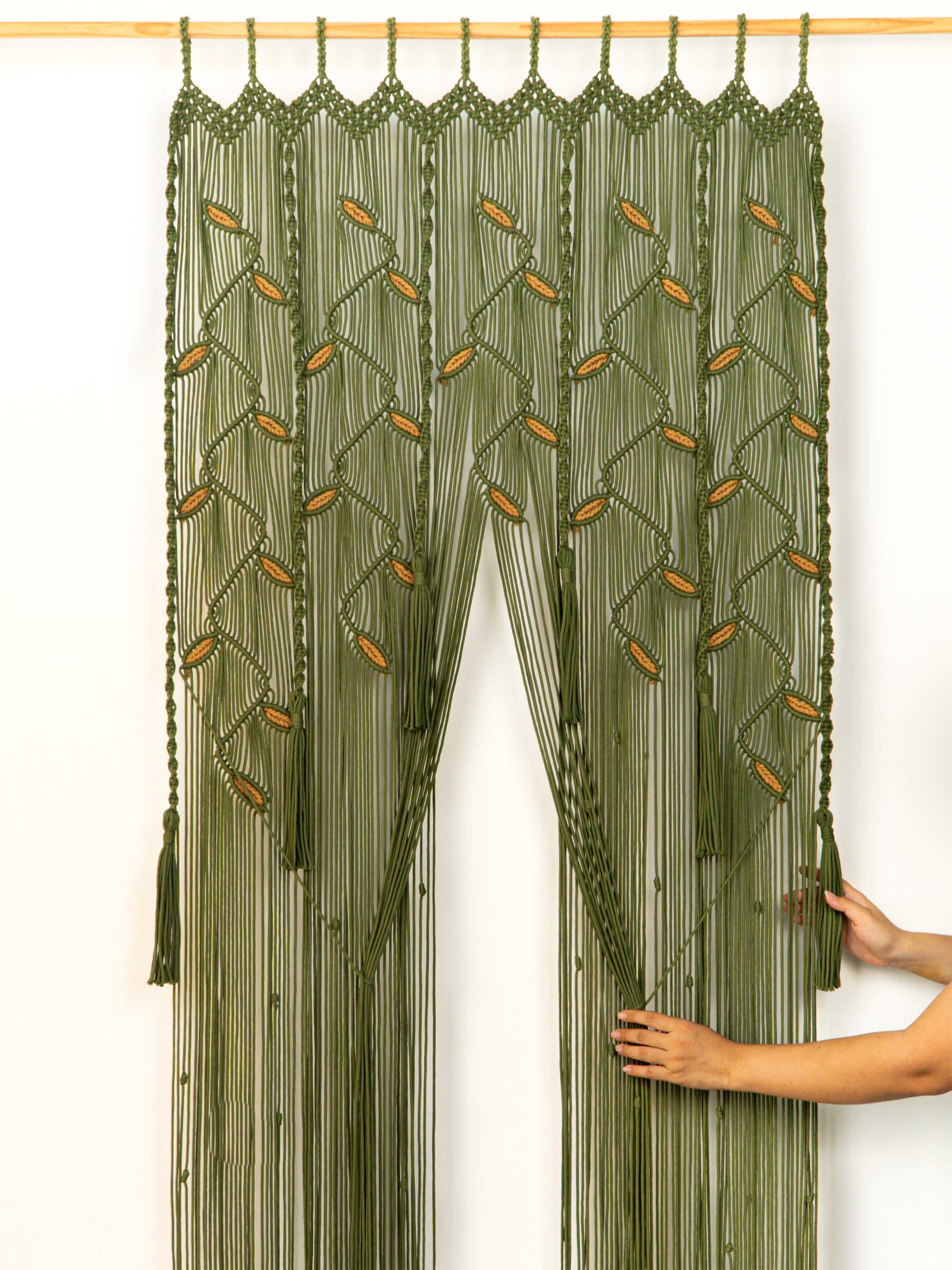 Green macrame curtain with tassels on a white background
