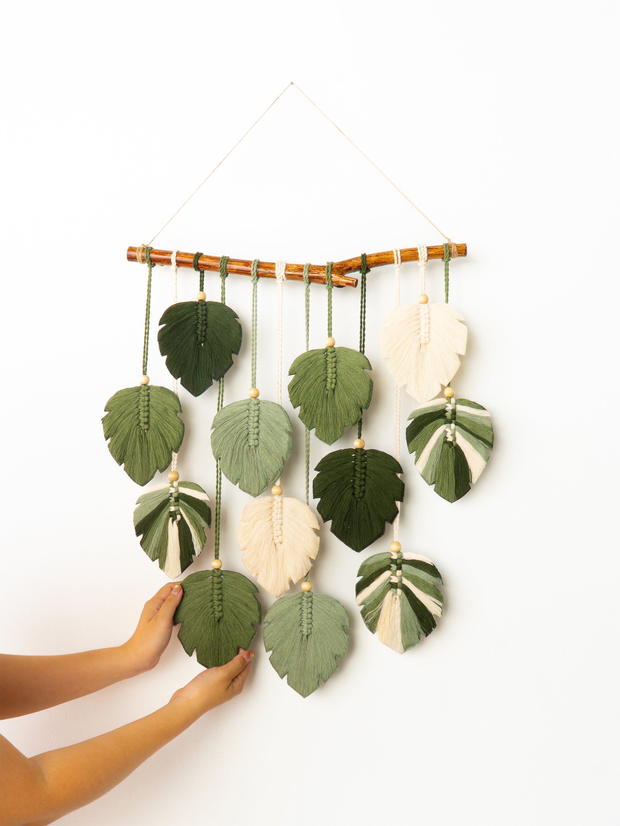 Handmade wall hanging with leaf-shaped fabric pieces on a white background