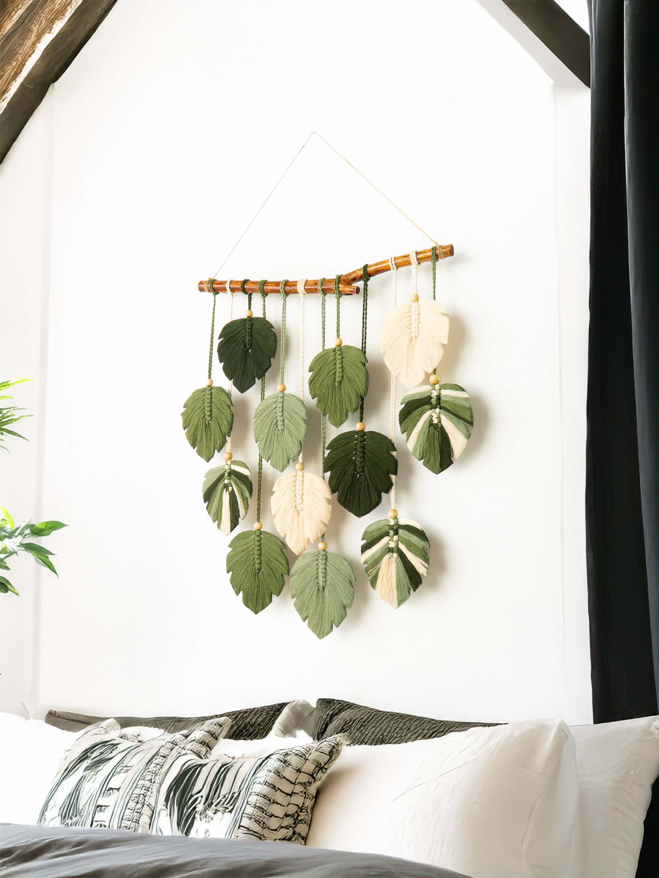 Decorative wall hanging with leaf-shaped ornaments on a white wall.