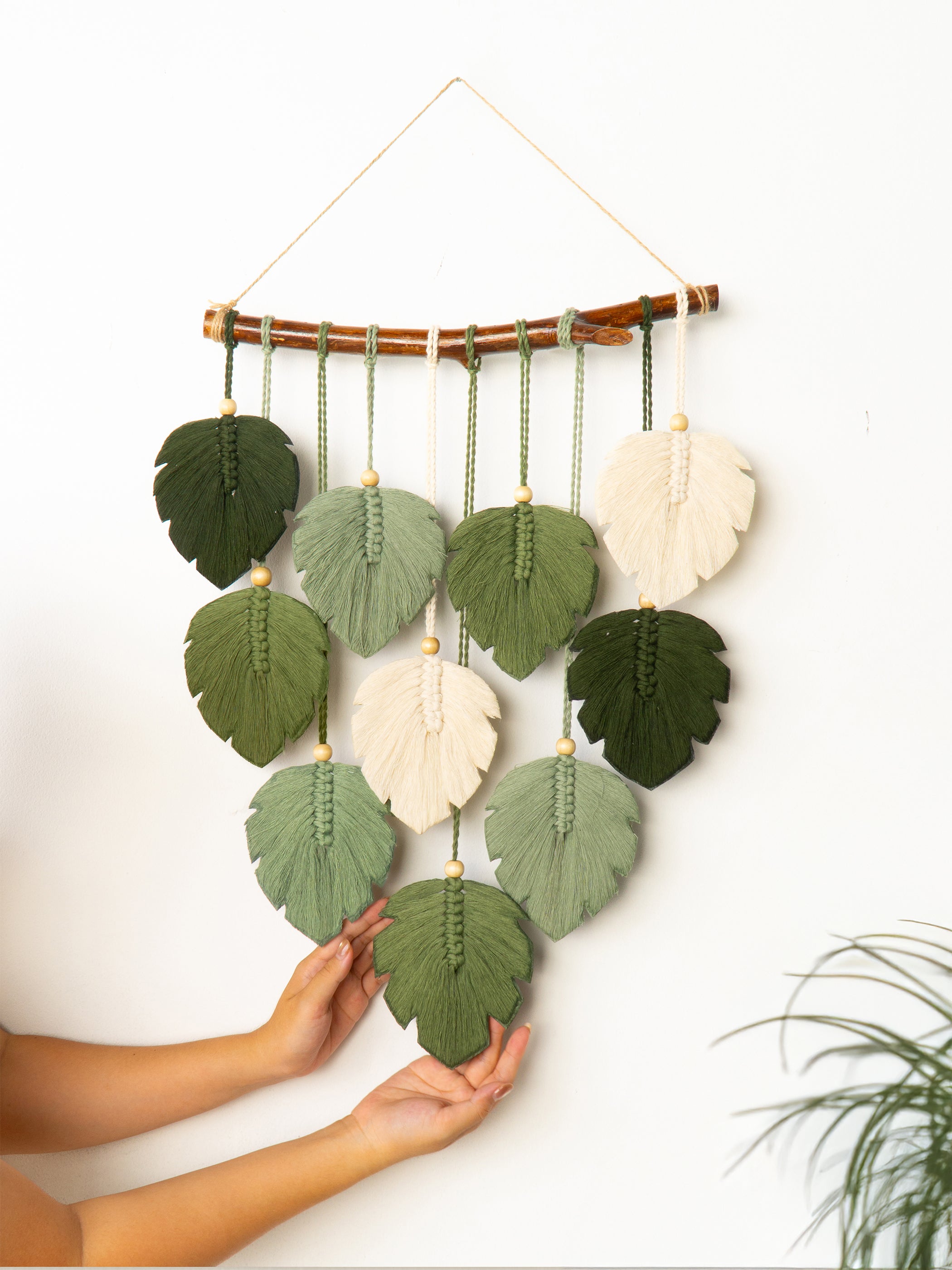 Handmade wall hanging with leaf-shaped felt pieces on a white background
