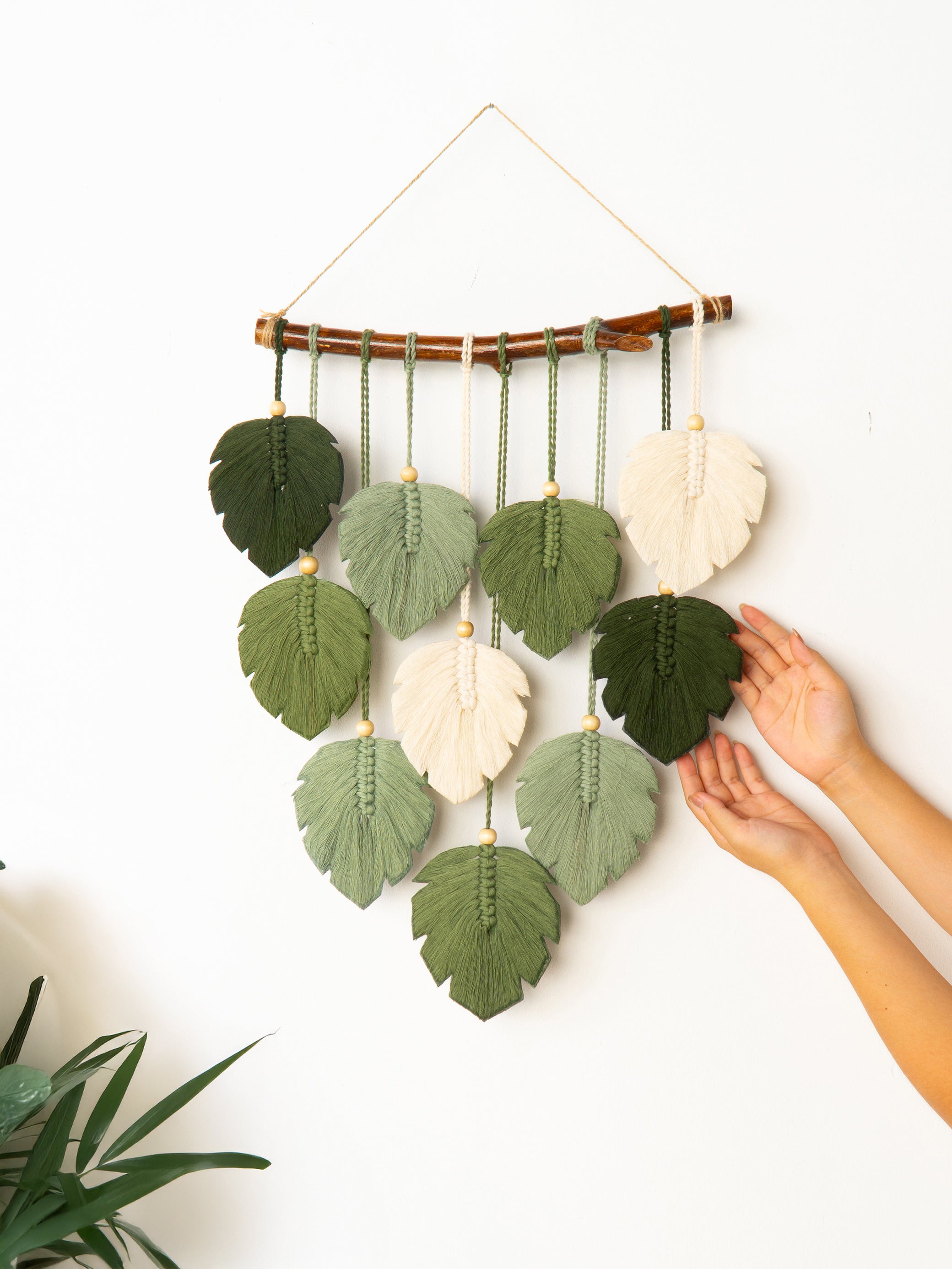 Handmade wall hanging with leaf-shaped green and white fabric pieces on a white background