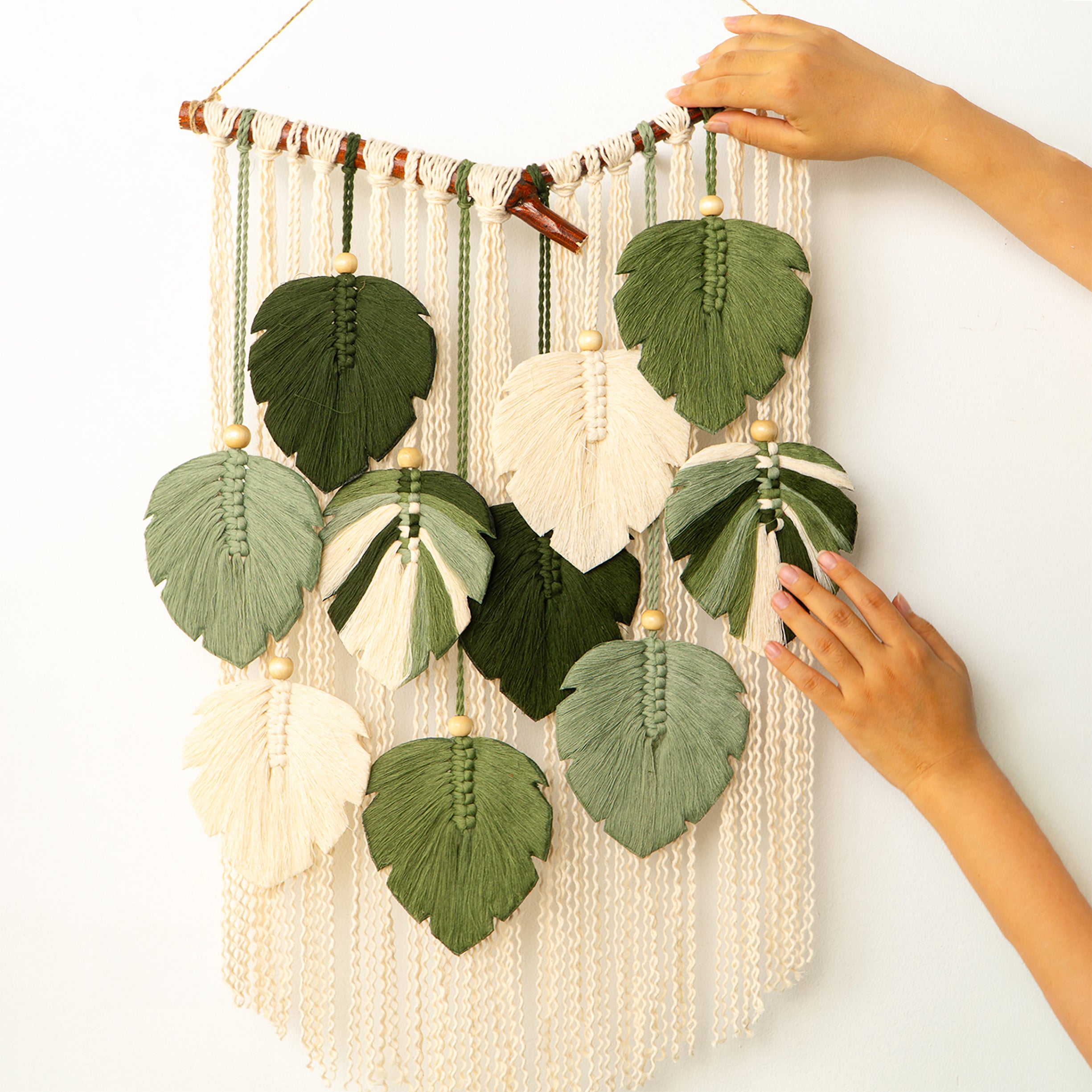 Decorative wall hanging with leaf-shaped leaves and beads on a white background