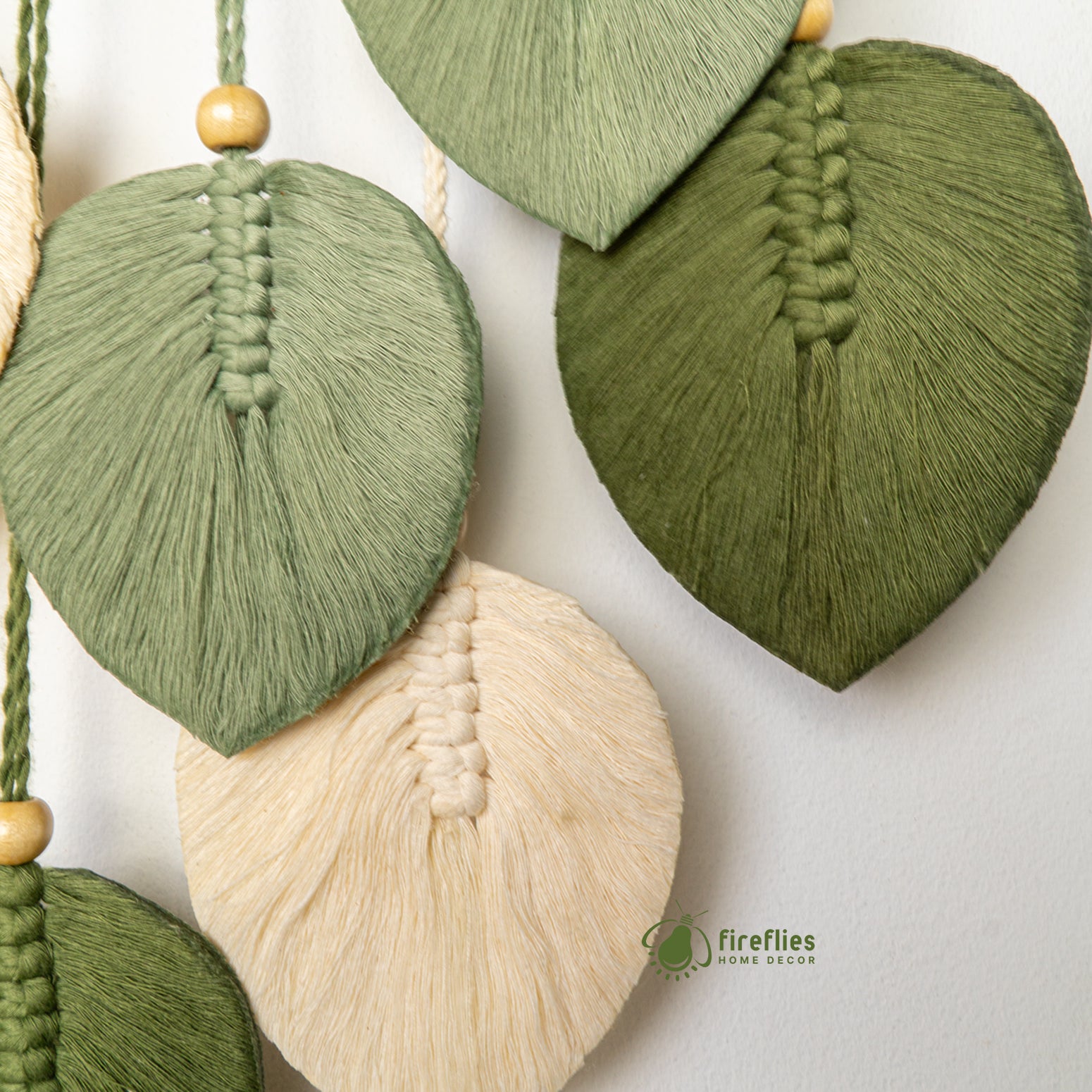 Decorative leaf-shaped tassels in green and beige on a white background with 'fireflies home decor' branding.