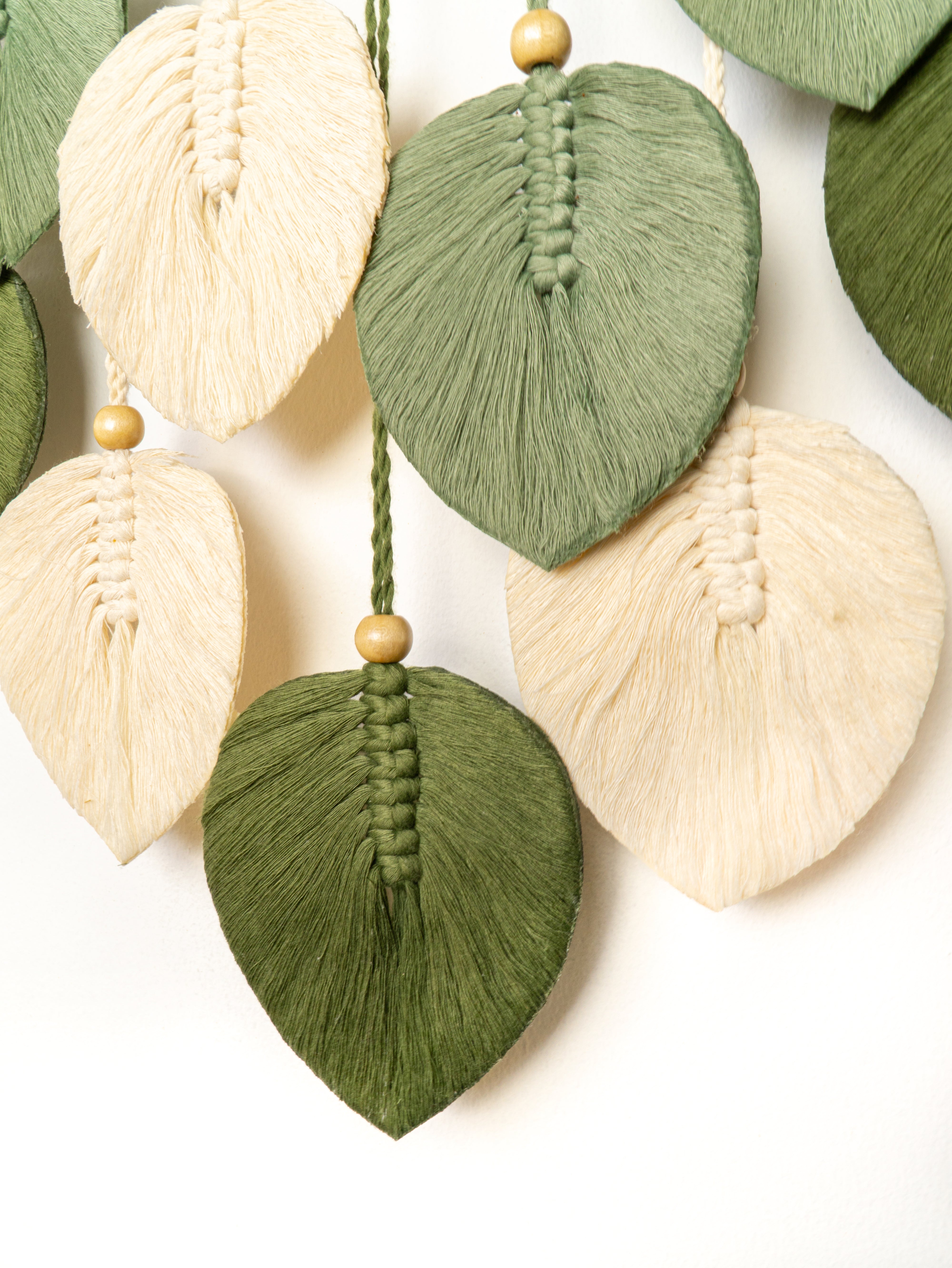 Decorative leaf-shaped tassels in green and beige on a white background