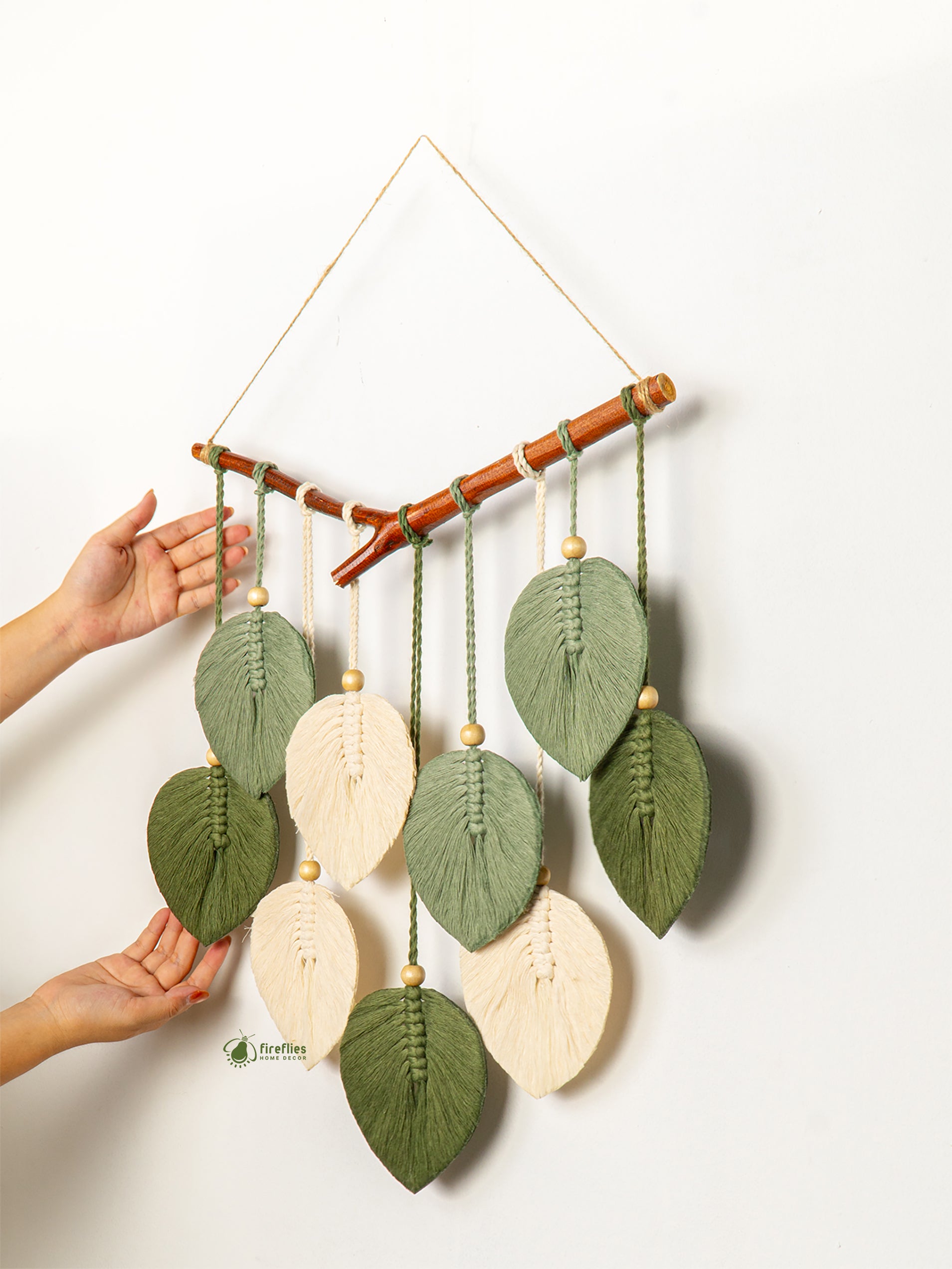 Handmade wall hanging with leaf-shaped decorations on a white background
