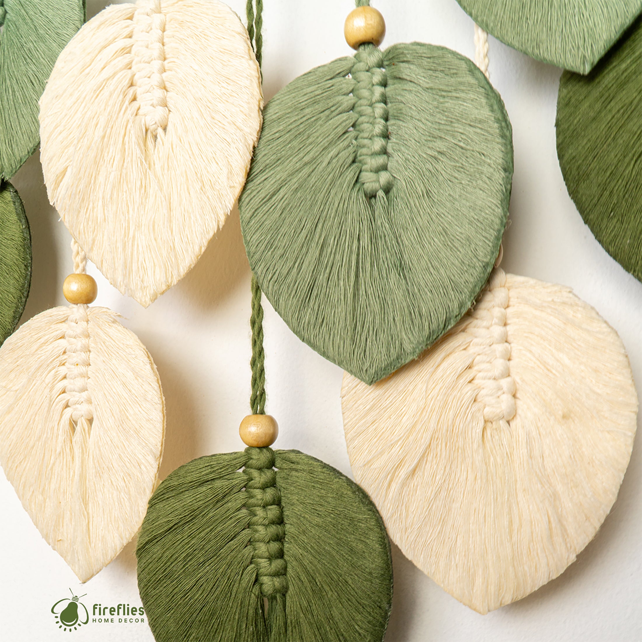 Decorative leaf-shaped tassels in green and beige on a white background with 'fireflies' brand logo.
