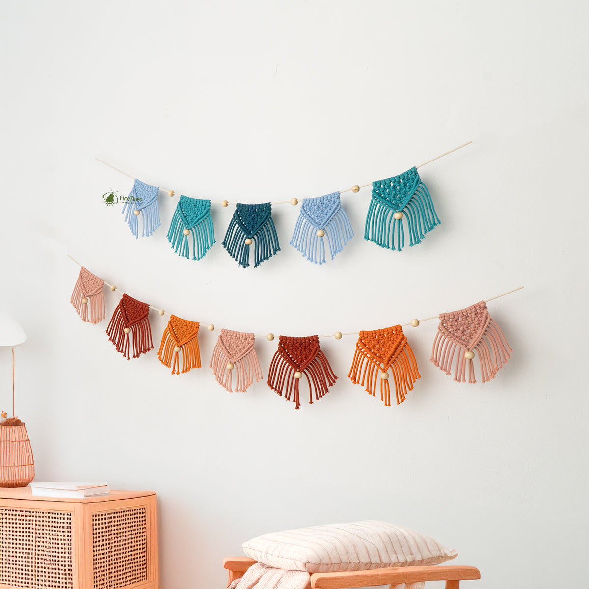 Colorful macrame wall hanging on a white wall with a wooden cabinet and lamp in the background.