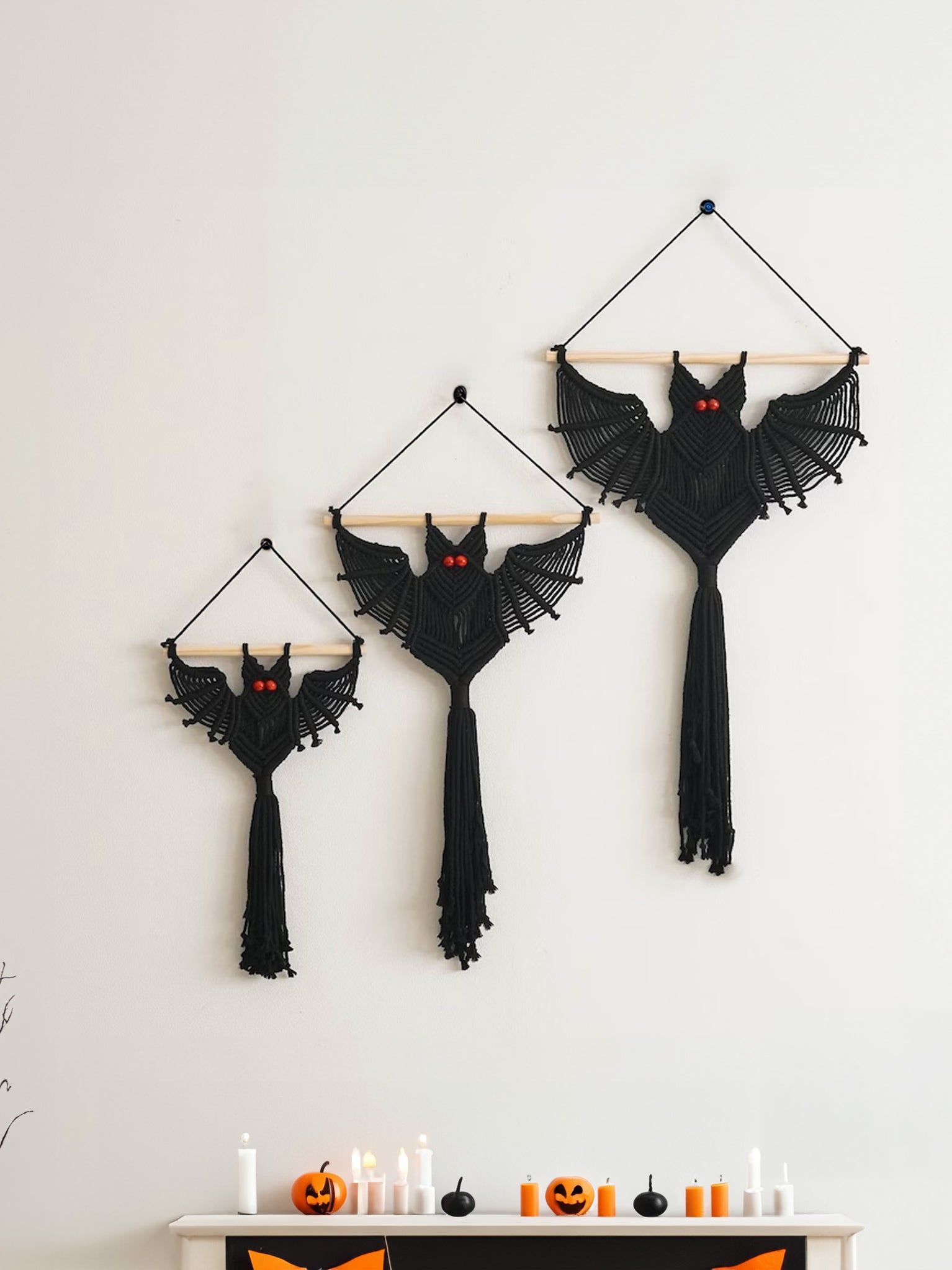 Hand-knotted black macrame bat wall art mounted on a smooth natural wood rod with a top hanging cord.   
