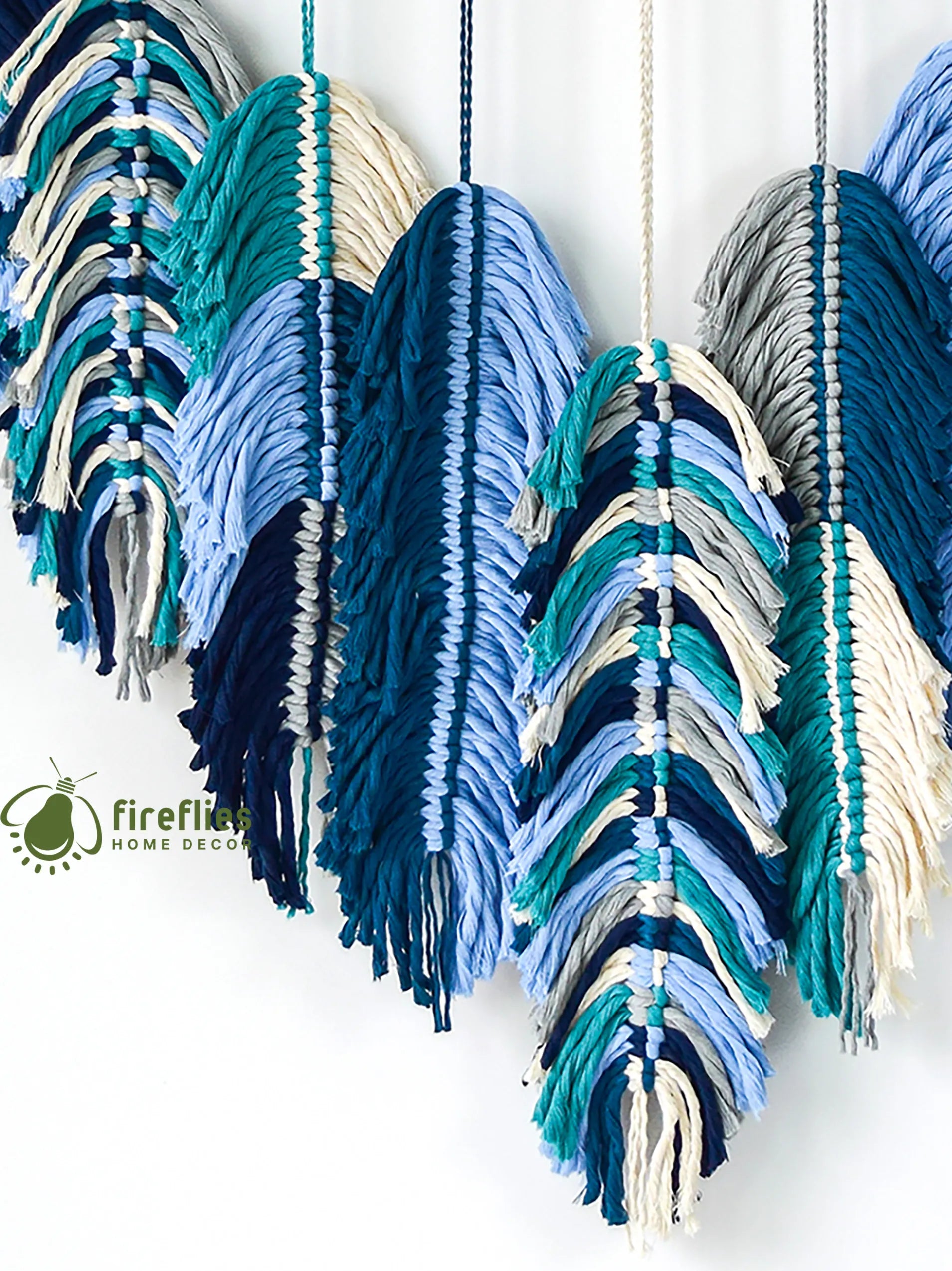 Colorful yarn wall hanging with a brand logo in the corner.