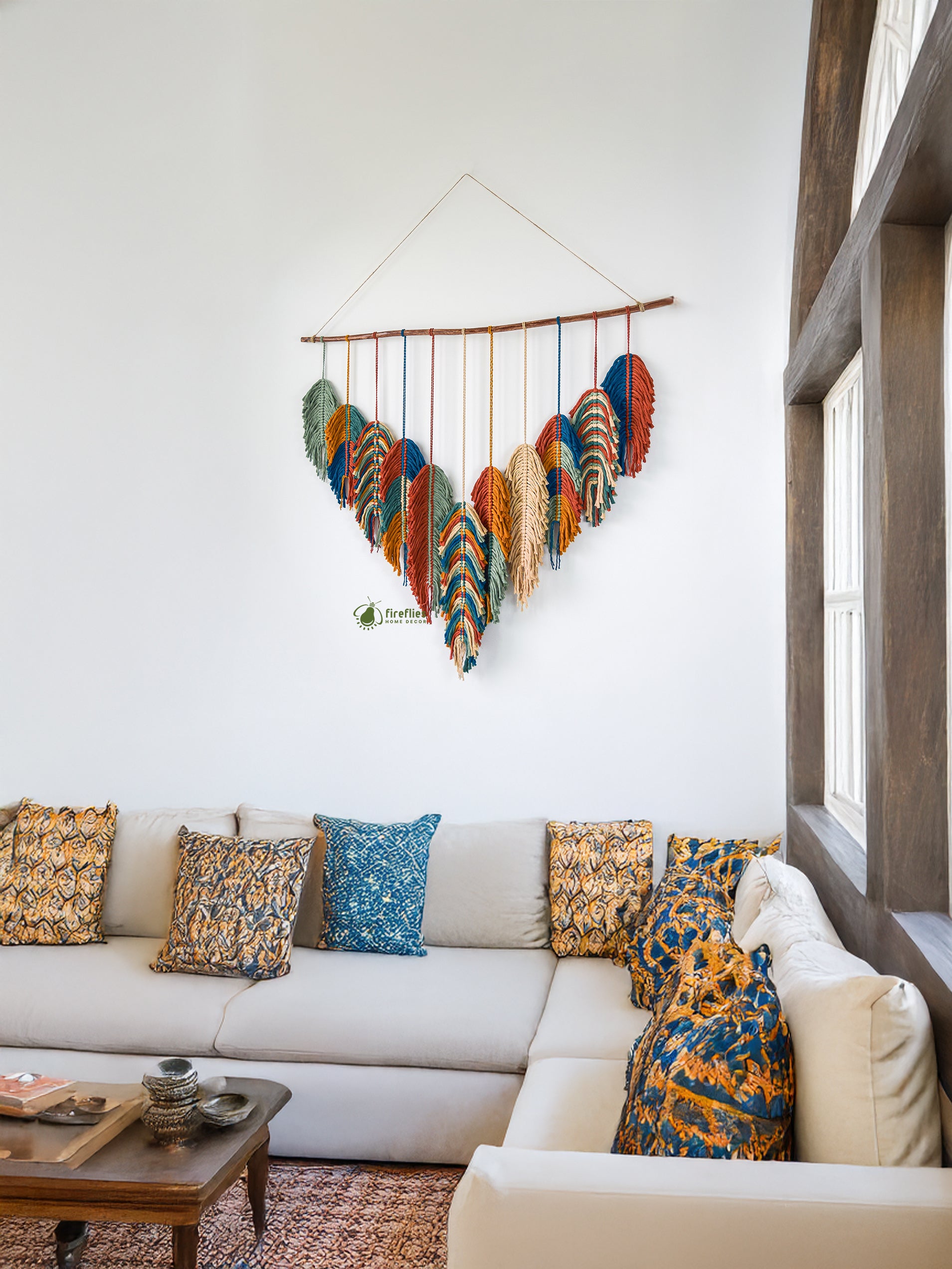 Decorative wall hanging above a white sofa with patterned cushions in a living room.