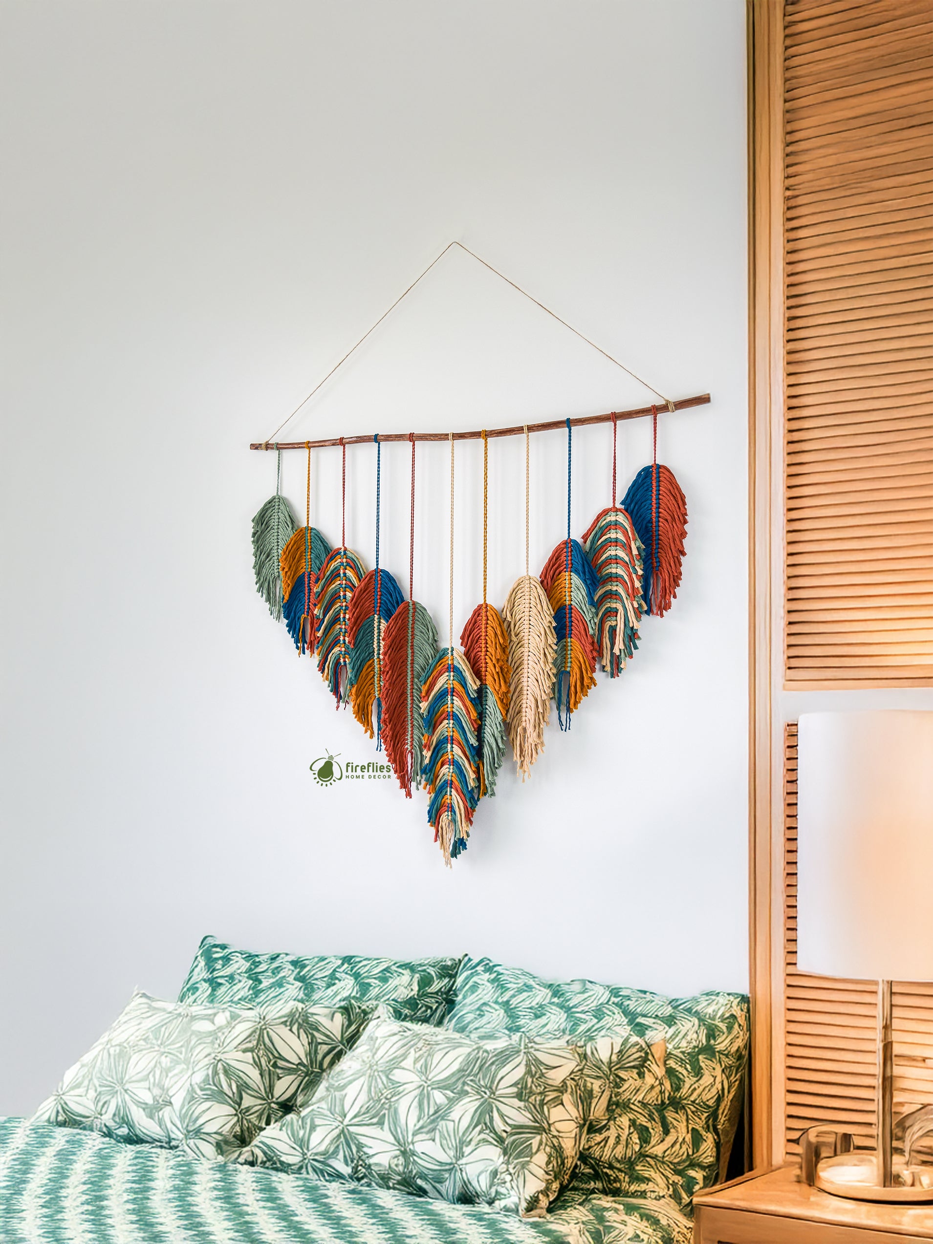Decorative wall hanging with colorful patterns on a white wall above a bed.