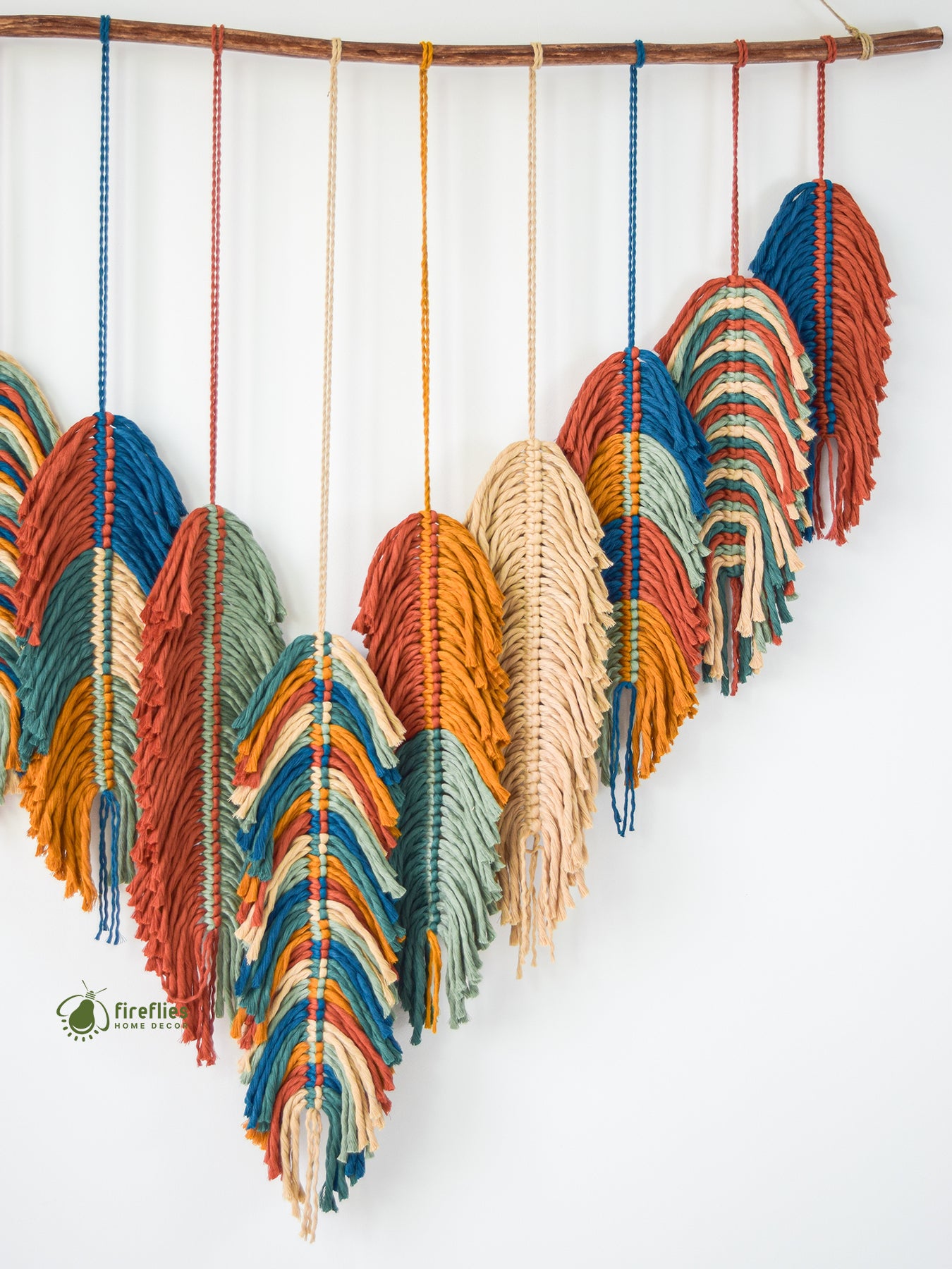 Colorful macrame wall hanging with leaf shapes on a white background