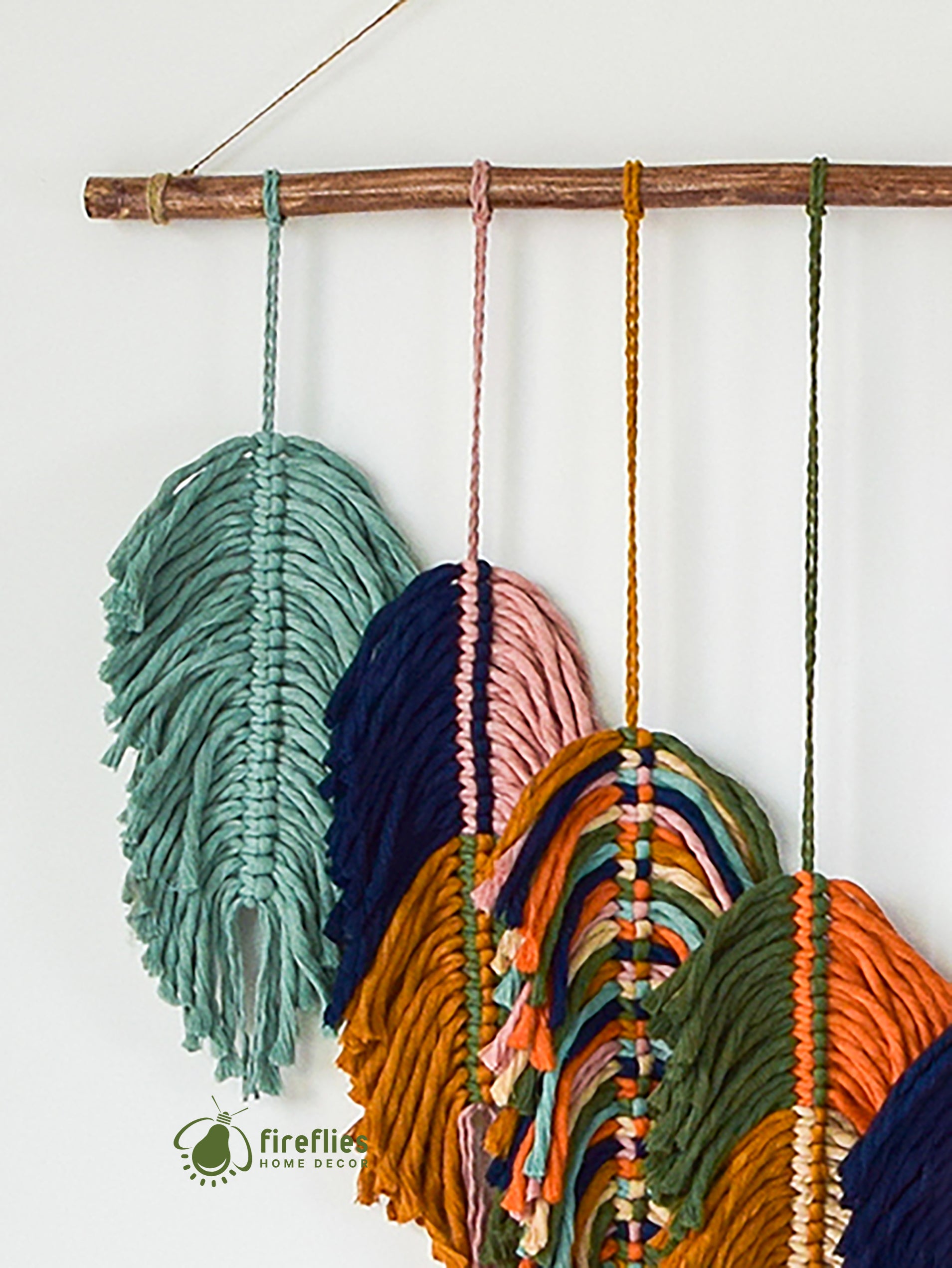 Colorful macrame wall hanging with wooden stick on a white background