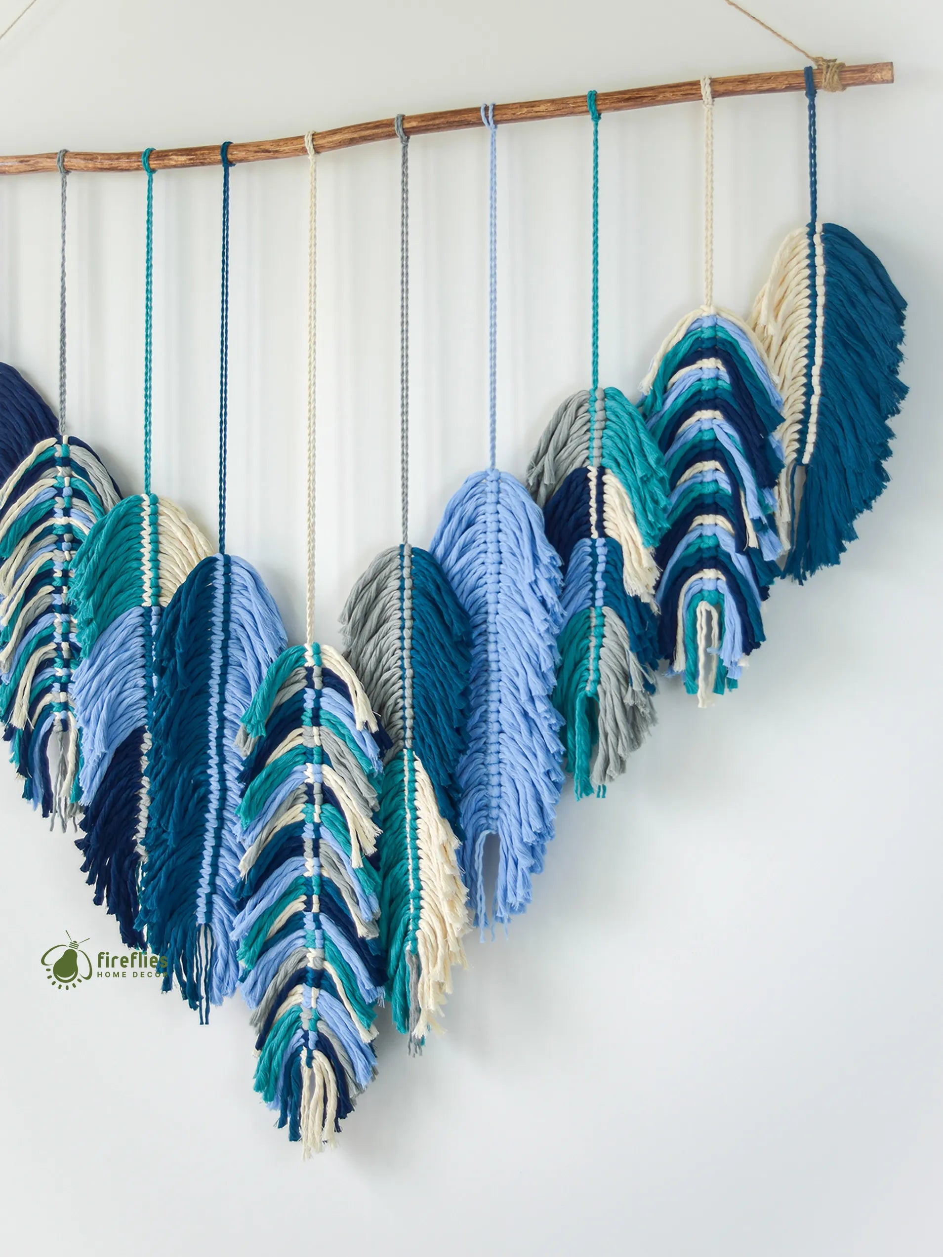 Decorative wall hanging with blue and green feathers on a white background