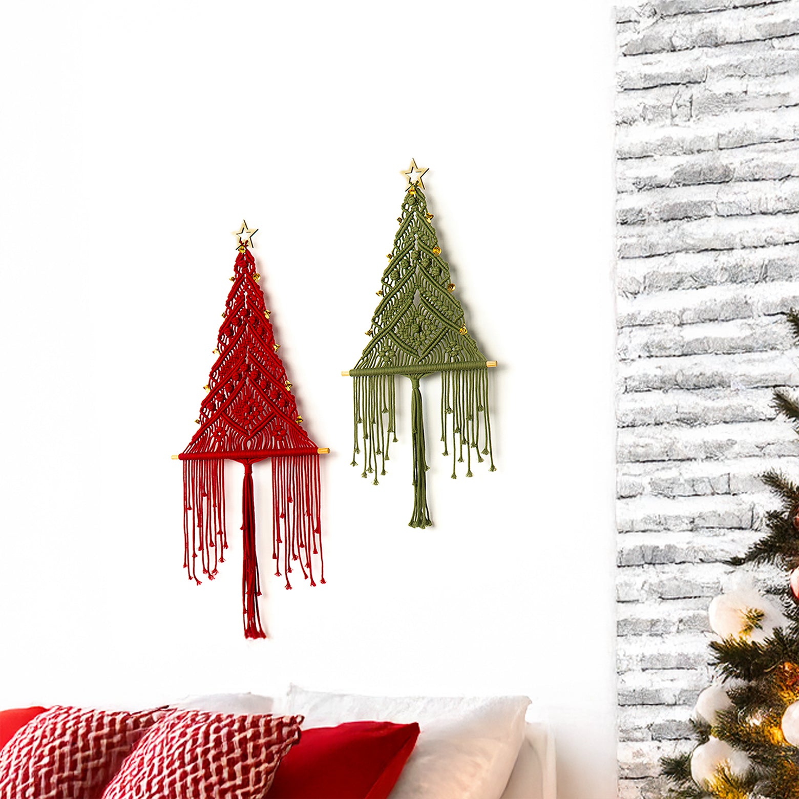 Two macrame Christmas tree wall hangings, one red and one green, against a white wall with a textured gray wall and Christmas tree in the background.