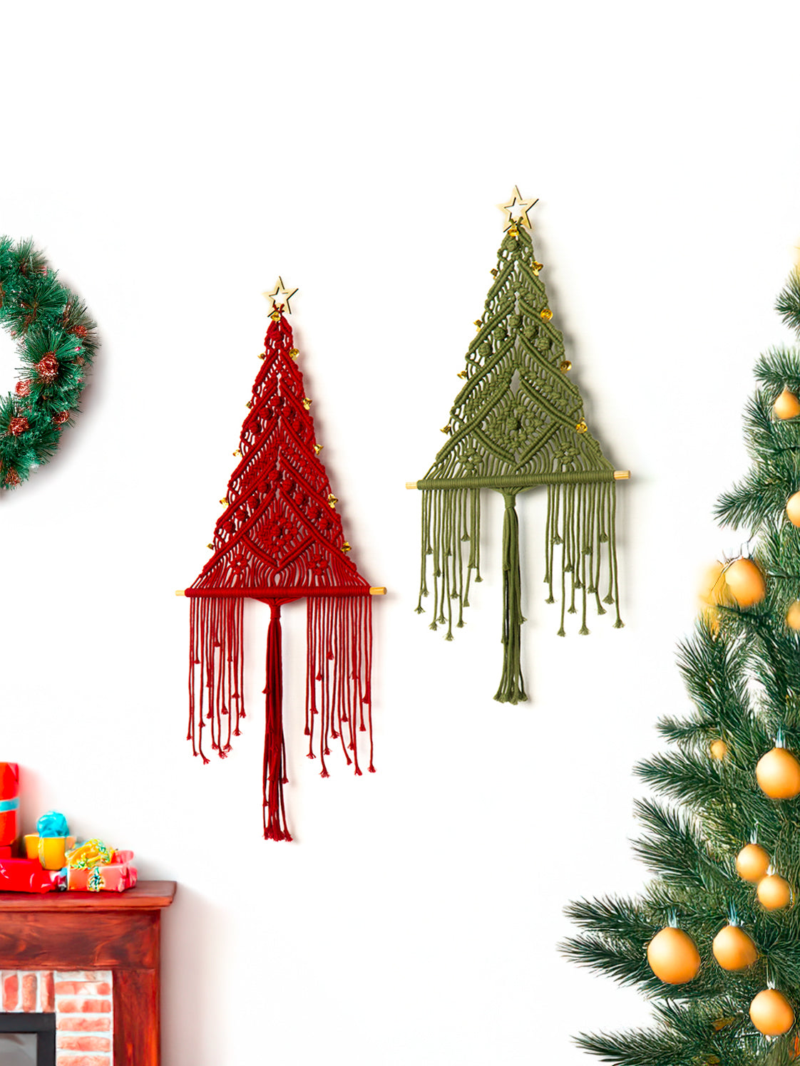 Decorative macramé Christmas trees in red and green on a white wall with a Christmas tree and wreath.