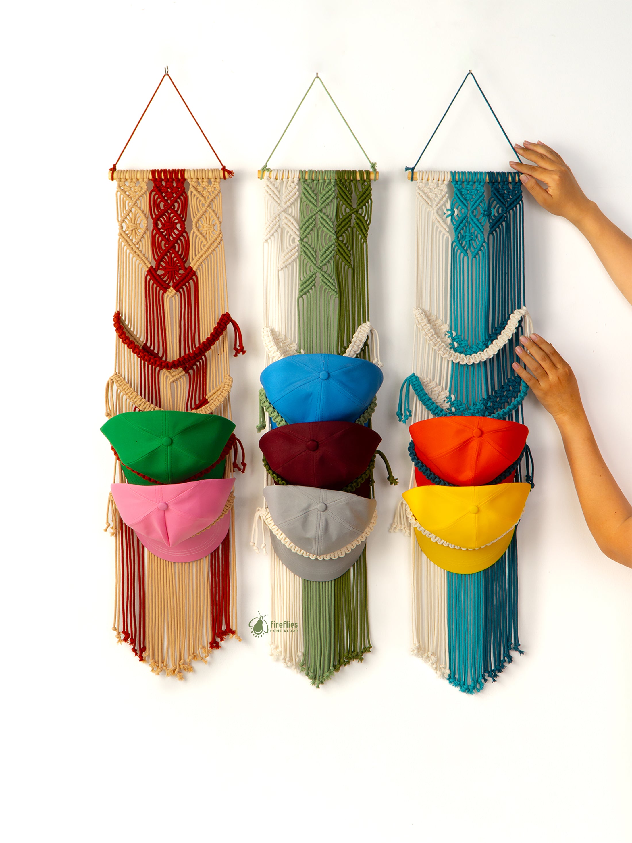 Colorful macrame wall hanging with small containers holding various colored hats.