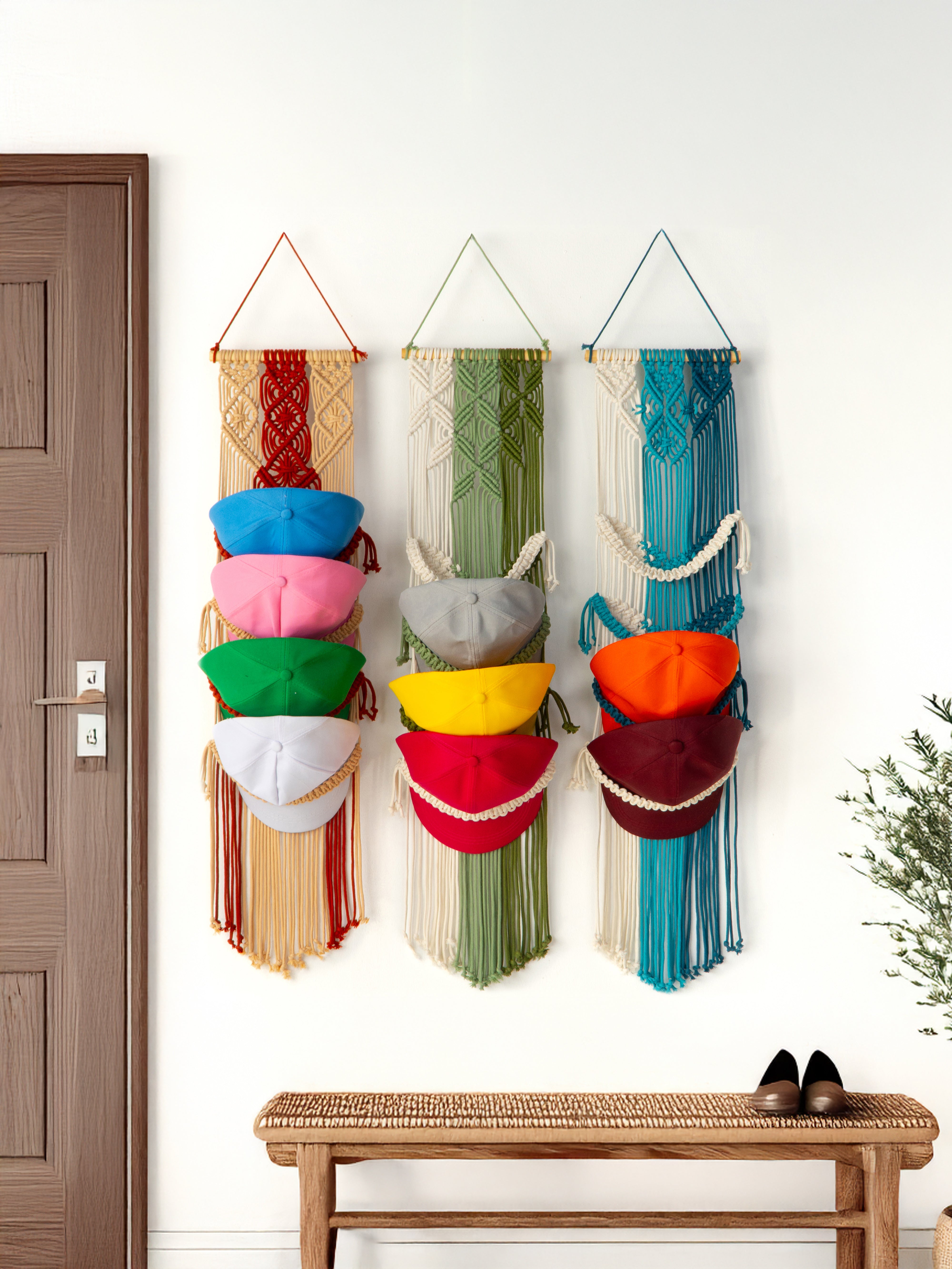 Colorful woven wall art with hats hanging on a white wall next to a wooden door.